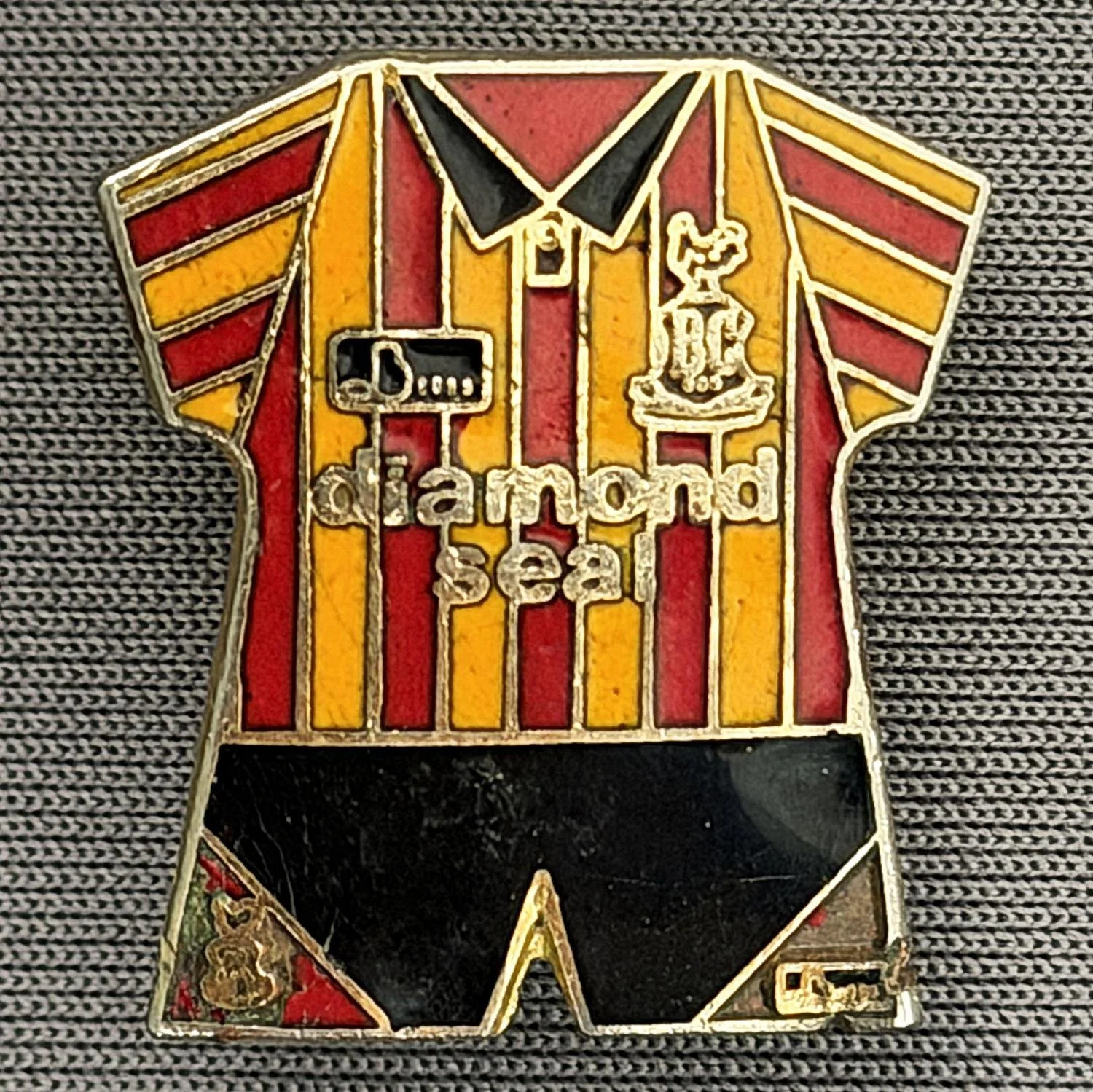 Reference Number: BCKIT011
Size: H 21.9 mm x W 19.6 mm
Pin Type: Brooch Pin
Plating: Gold
Value: £6
Manufacturer: Unknown
Comments: 1994/95 Kit, Enamel MissingFrom Bottom Of Shorts