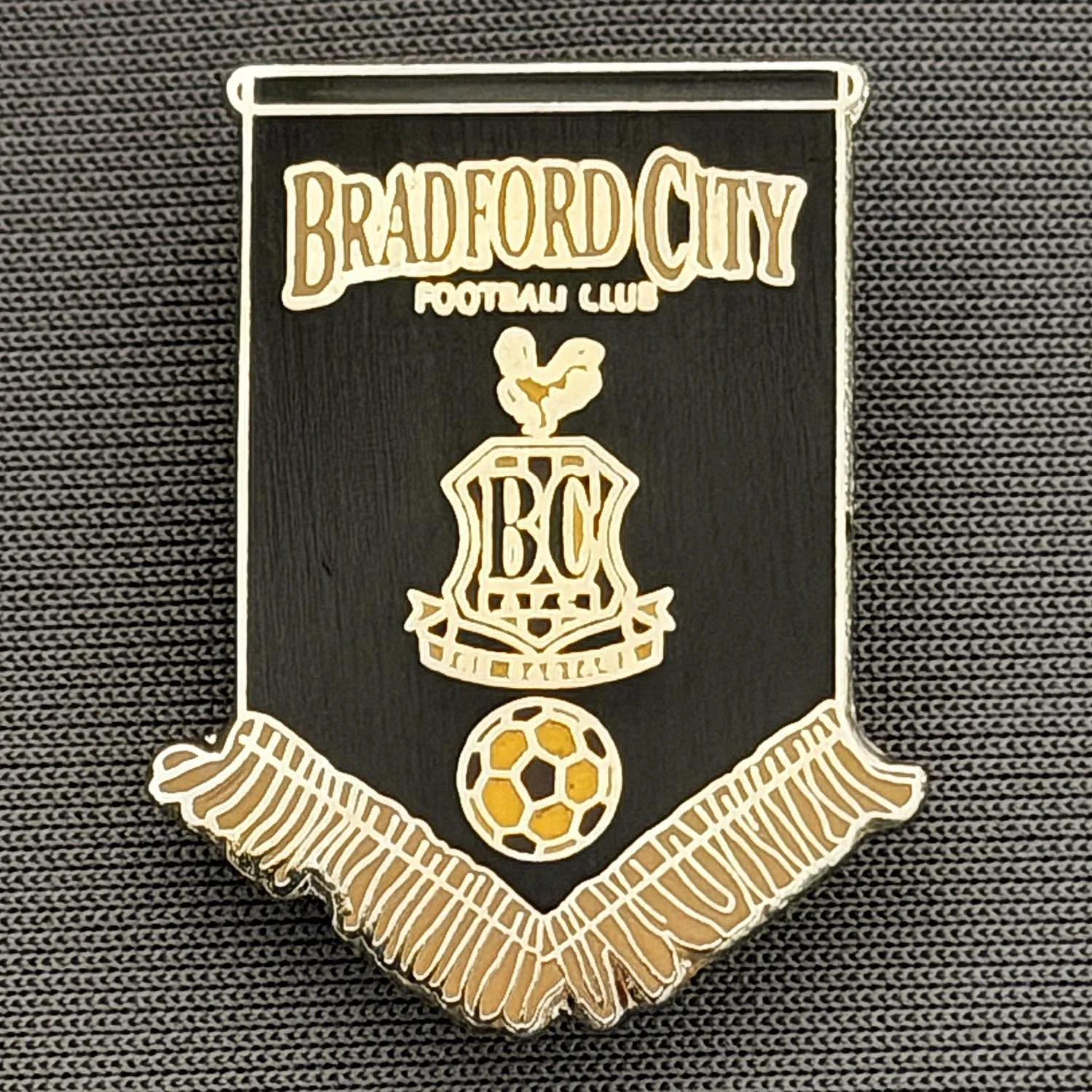 Reference Number: BCBCFC062
Size: H 28.1 mm x W 22.1 mm
Pin Type: Brooch Pin
Plating: Gold
Value: £6
Manufacturer: Andy Stokes
Comments: Black & Coffee Bradford City Pennant