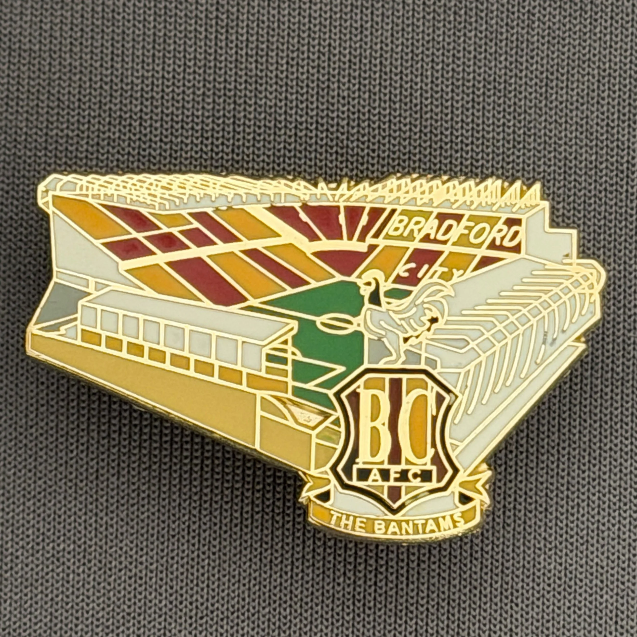 Reference Number: BCVP019
Size: H 20.5 mm x W 32.1 mm
Pin Type: Metal Clutch
Plating: Gold
Value: £4
Manufacturer: Dan Lloyd
Comments: Valley Parade Stadium with Coloured City Logo