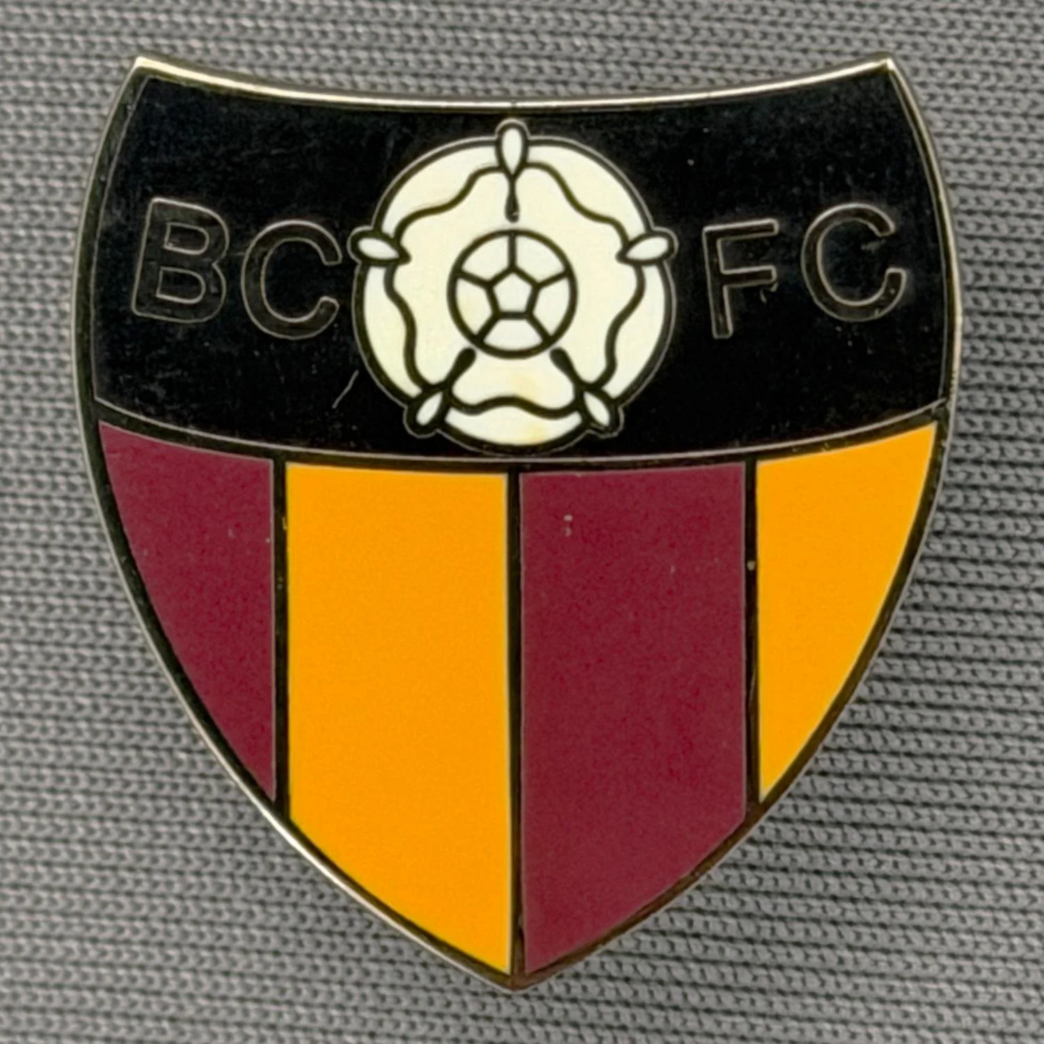 Reference Number: BCYR024
Size: H 22.8 mm x W 21.2 mm
Pin Type: Brooch Pin
Plating: Black Nickel
Value: £6
Manufacturer: Unknown
Comments: BCFC Yorkshire Rose Black, Claret & Amber Shield. Smaller version.