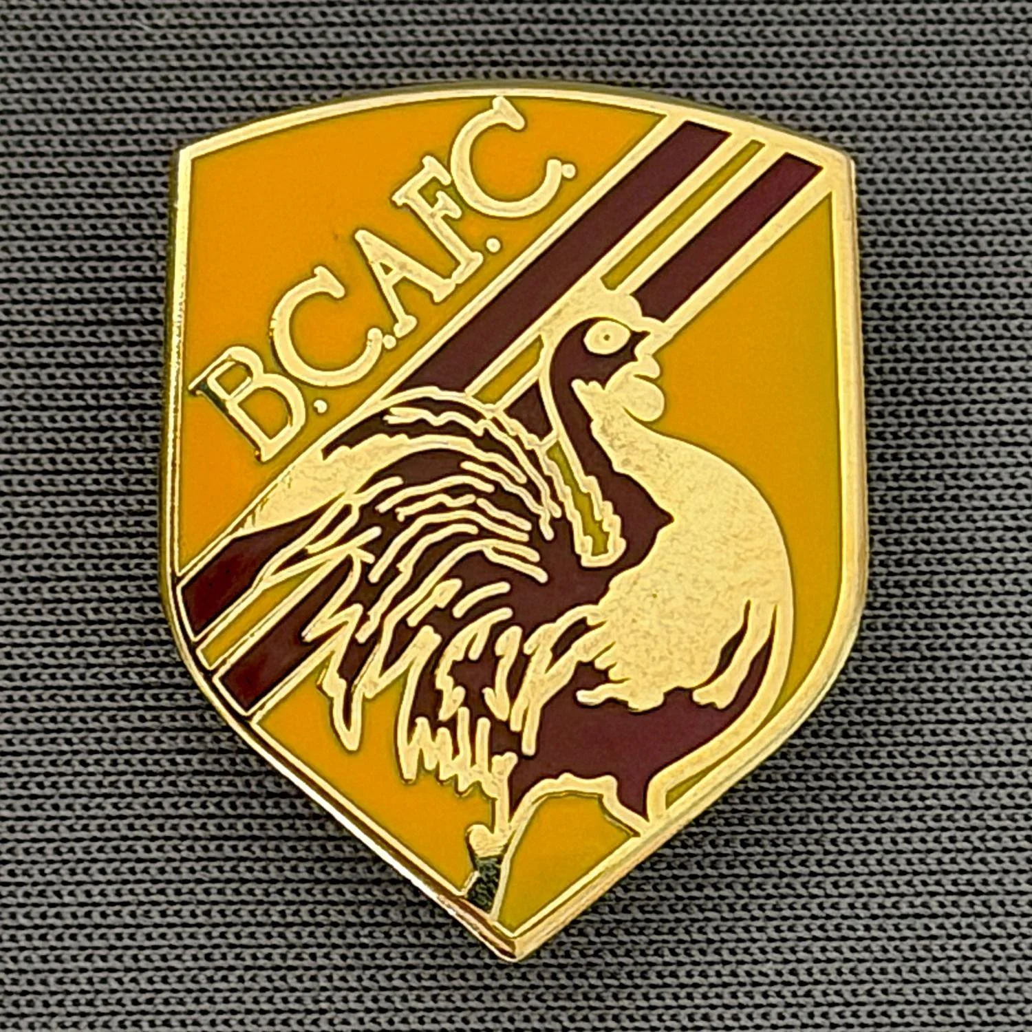 Reference Number: BCBAN047
Size: H 24.1 mm x W 19.4. mm
Pin Type: Brooch Pin
Plating: Gold
Value: £6
Manufacturer: Unknown
Comments: Amber & Claret Bantam Shield