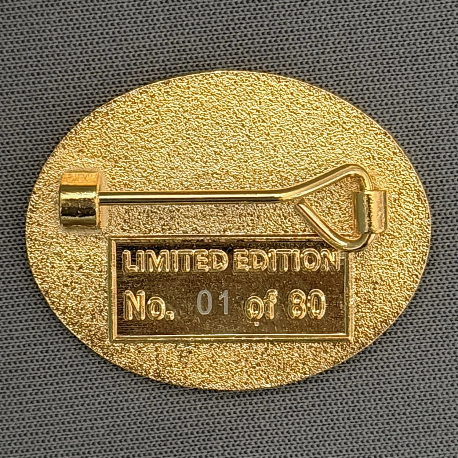 Gold-colored limited edition badge with a safety pin and serial number