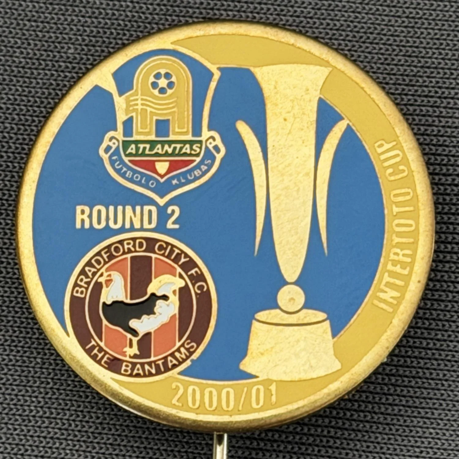 Reference Number: BCRUS037
Size: D 25 mm 
Pin Type: Metal Stick Pin
Plating: Gold
Value: £12
Manufacturer: Unknown
Comments: FK Atlantas Inter Toto Cup, City Logo, Blue & Yellow Version