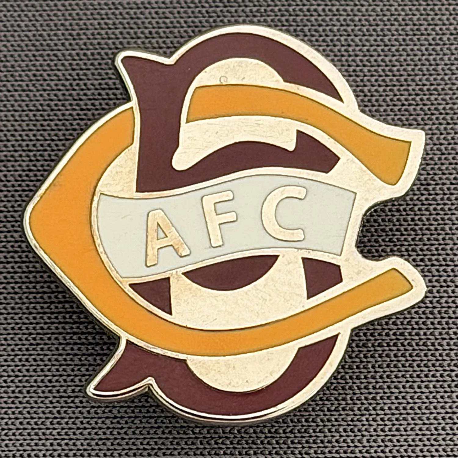 Reference Number: BCC&L070
Size: H 22.1 mm x 22  mm
Pin Type: Brooch Pin
Plating: Silver
Value: £6
Manufacturer: Unknown
Comments: BCFC Ayrton Scroll Amber & Claret