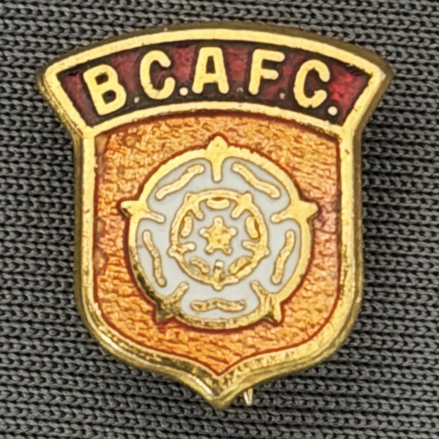 Reference Number: BCYR001
Size: H 14.5 mm x W 13.3 mm
Pin Type: Brooch Pin
Plating: Gold
Value: £8
Manufacturer: Unknown
Comments: Small Amber & Claret Yorkshire Rose Shield
