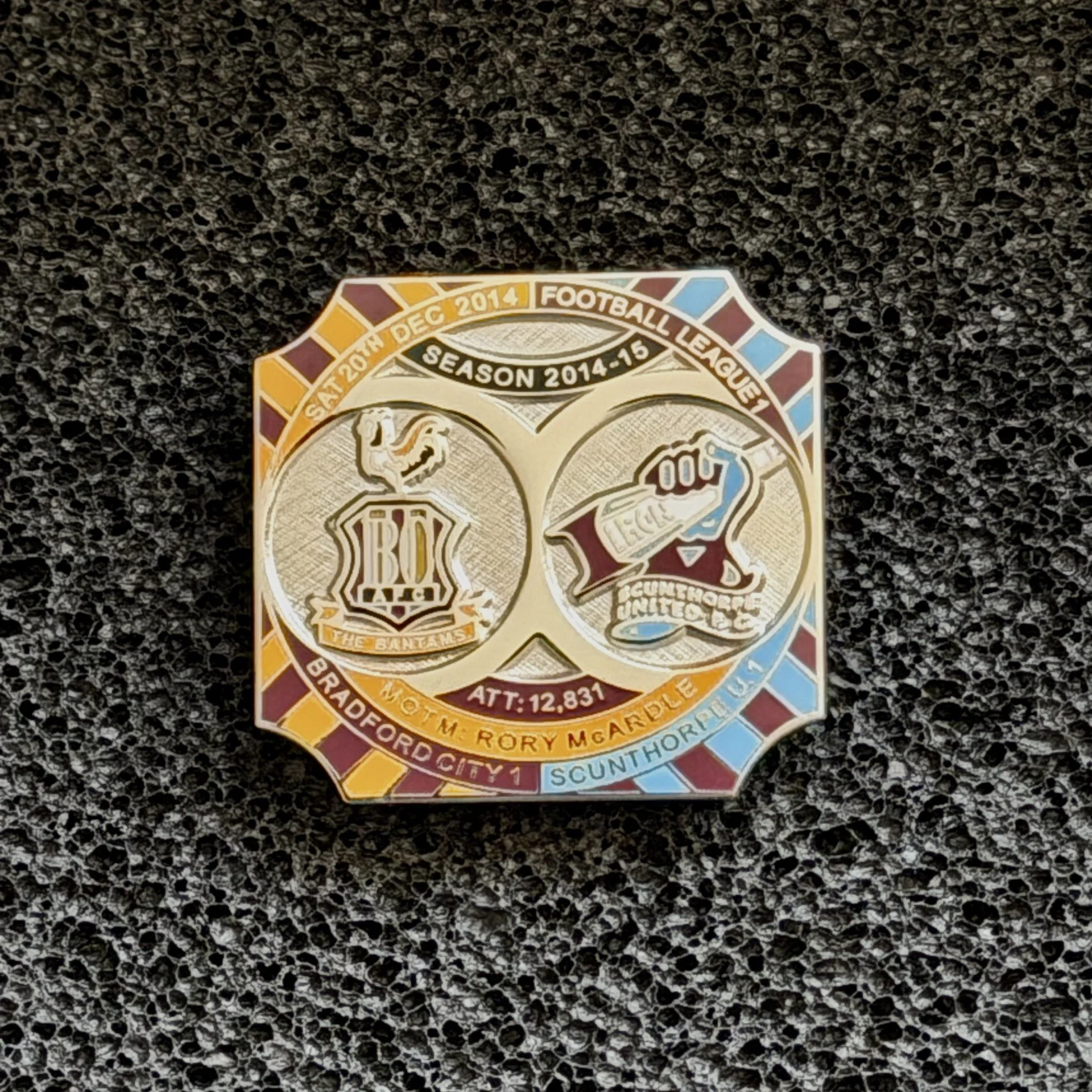 Close-up of a sticker commemorating the 2014-15 season of the San Francisco Giants baseball team, featuring gold, red, white, and blue details, set on a black, textured surface.