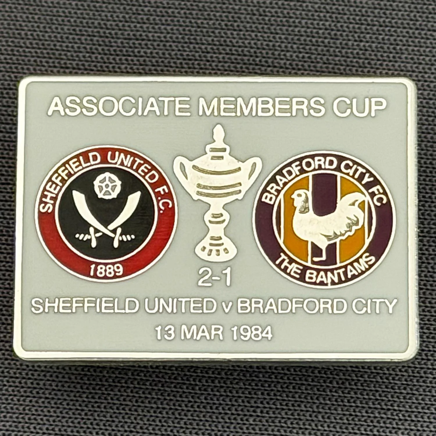 Reference Number: BCOFIX060
Size: H 18.9 mm x W 25.9 mm
Pin Type: Brooch Pin
Plating: Silver
Value: £6
Manufacturer: Unknown
Comments: Sheffield United v Bradford City Associate Members Cup 1984, White Version