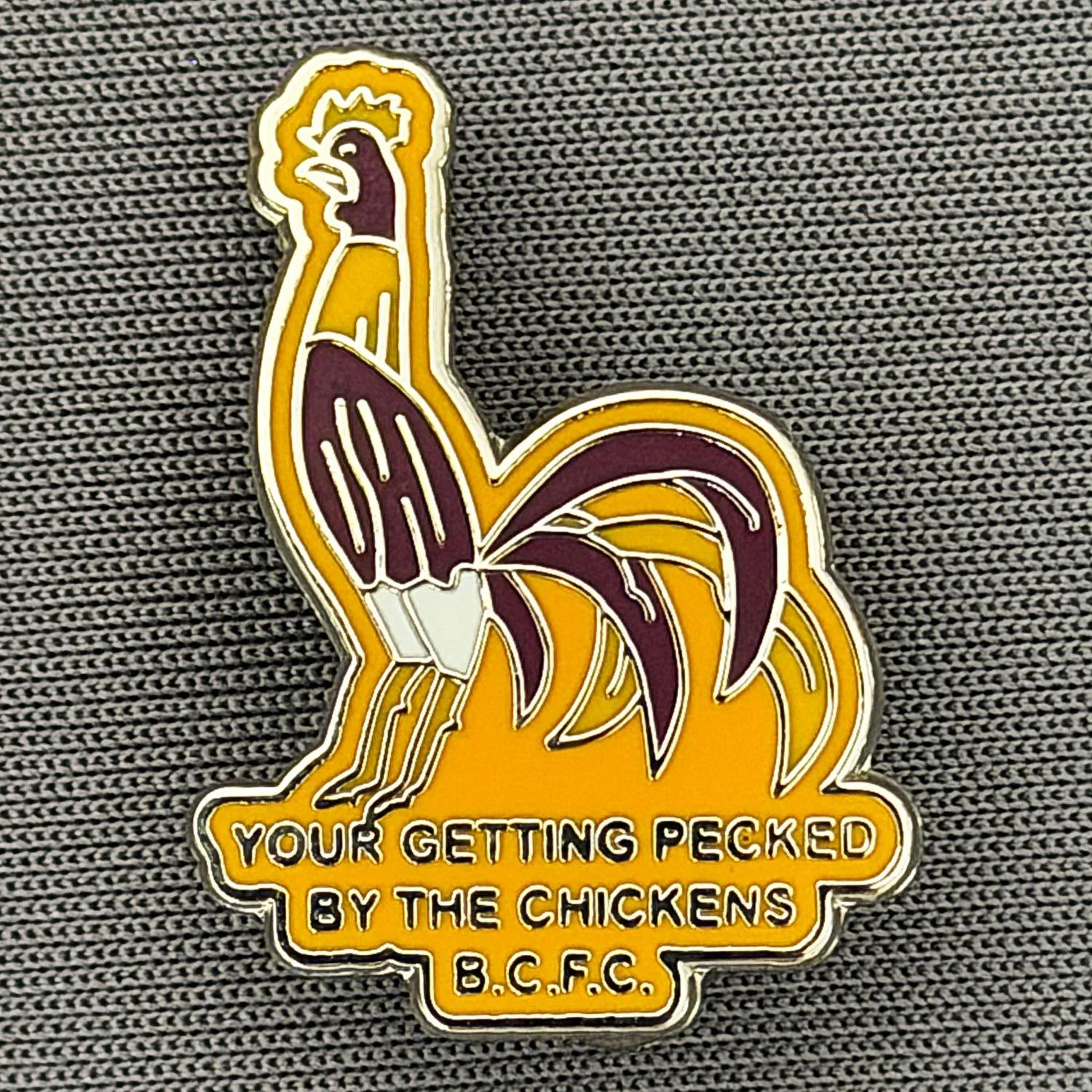Reference Number: BCBAN062
Size: H 24.7 mm x W 17.9 mm
Pin Type: Brooch Pin
Plating: Silver
Value: £6
Manufacturer: Unknown
Comments: Claret & Amber Bantam, Pecked By The Chickens 