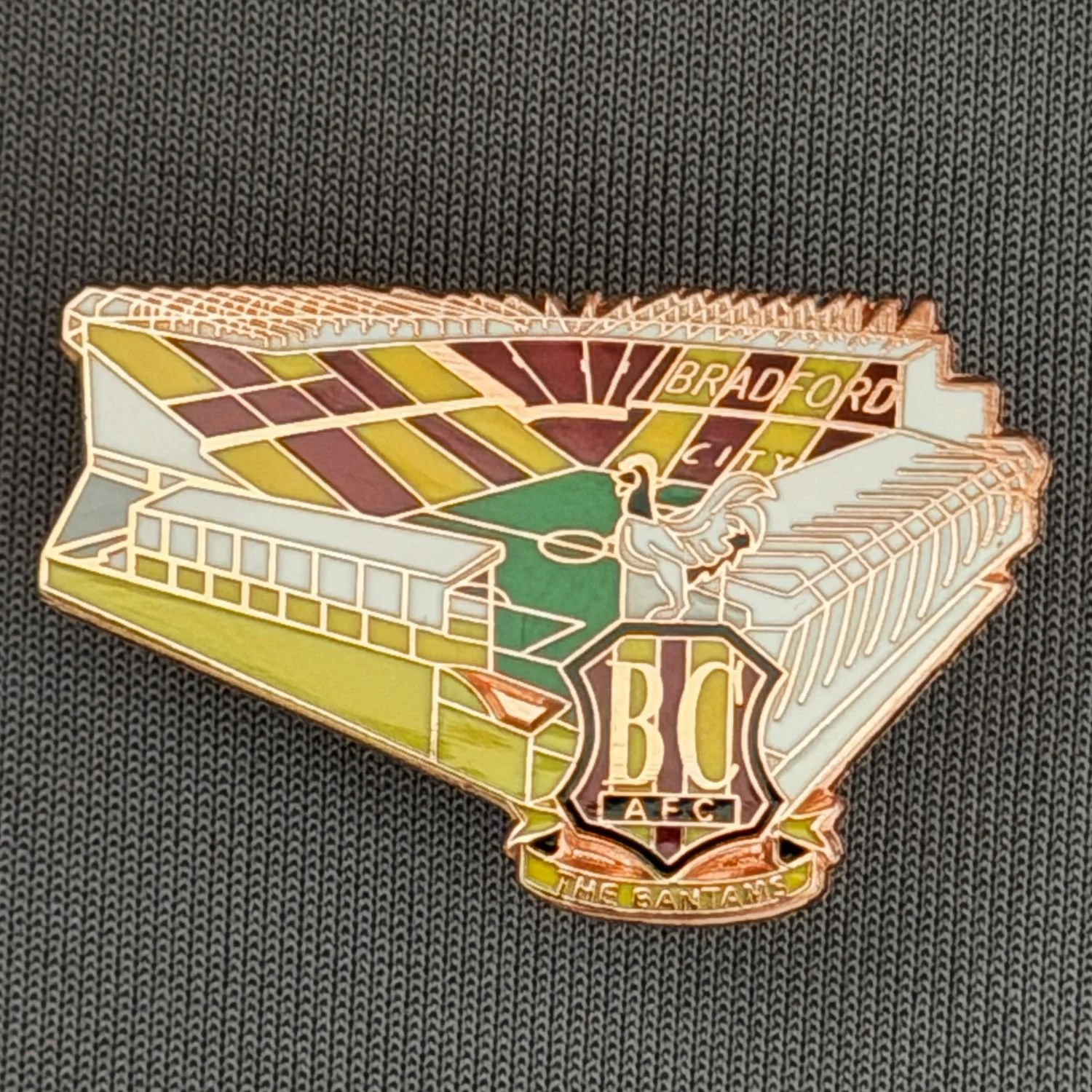 Reference Number: BCVP025
Size: H 20.5 mm x W 32.1 mm
Pin Type: Metal Clutch
Plating: Nickel
Value: £4
Manufacturer: Dan Lloyd
Comments: Valley Parade Stadium with Enamel City Logo