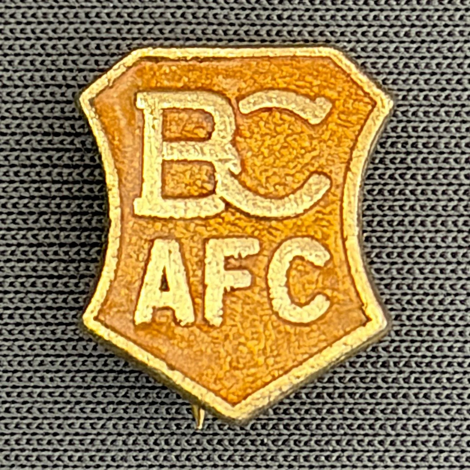 Reference Number: BCBCFC011
Size: H 14.4 mm x W 12 mm
Pin Type: Brooch Pin
Plating: Gold
Value: £8
Manufacturer: Unknown
Comments: Amber BCAFC Shield