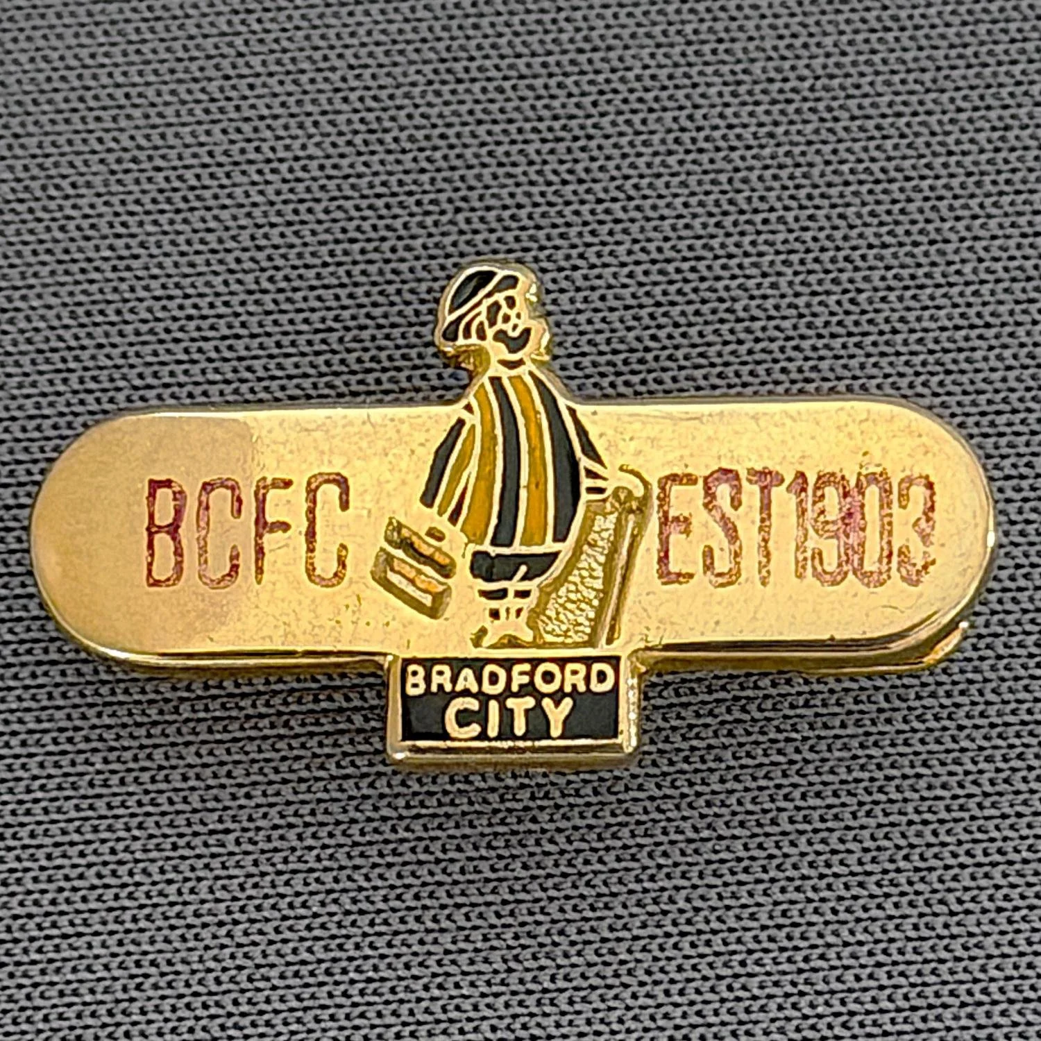 Reference Number: BCGEN027
Size: H 13.2 mm x W 24.8 mm
Pin Type: Brooch Pin
Plating: Gold
Value: £8
Manufacturer: Unknown
Comments: Horizontal Bar, City Gent, Claret Letters