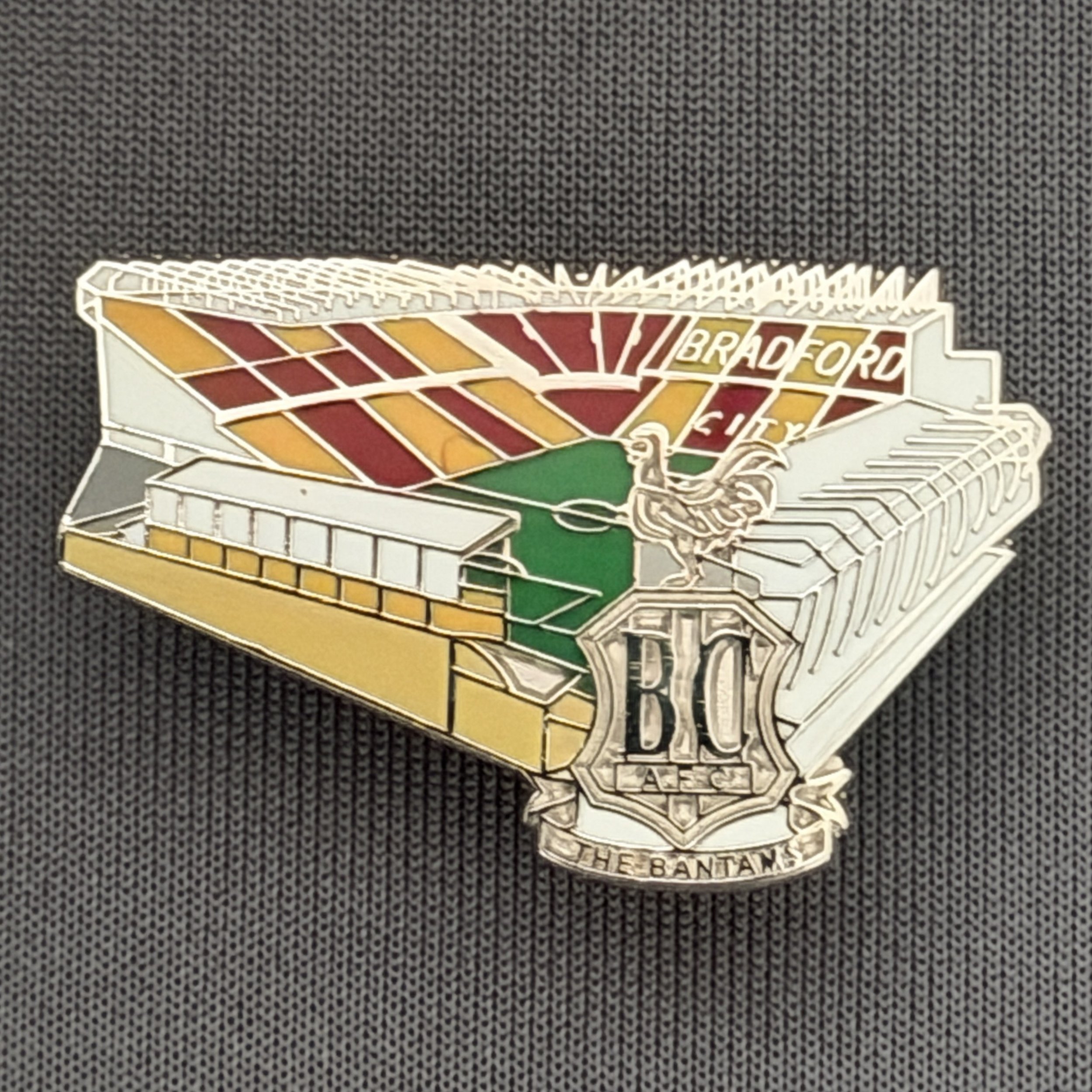 Reference Number: BCVP022
Size: H 20.5 mm x W 32.1 mm
Pin Type: Metal Clutch
Plating: Nickel
Value: £4
Manufacturer: Dan Lloyd
Comments: Valley Parade Stadium with Metal City Logo