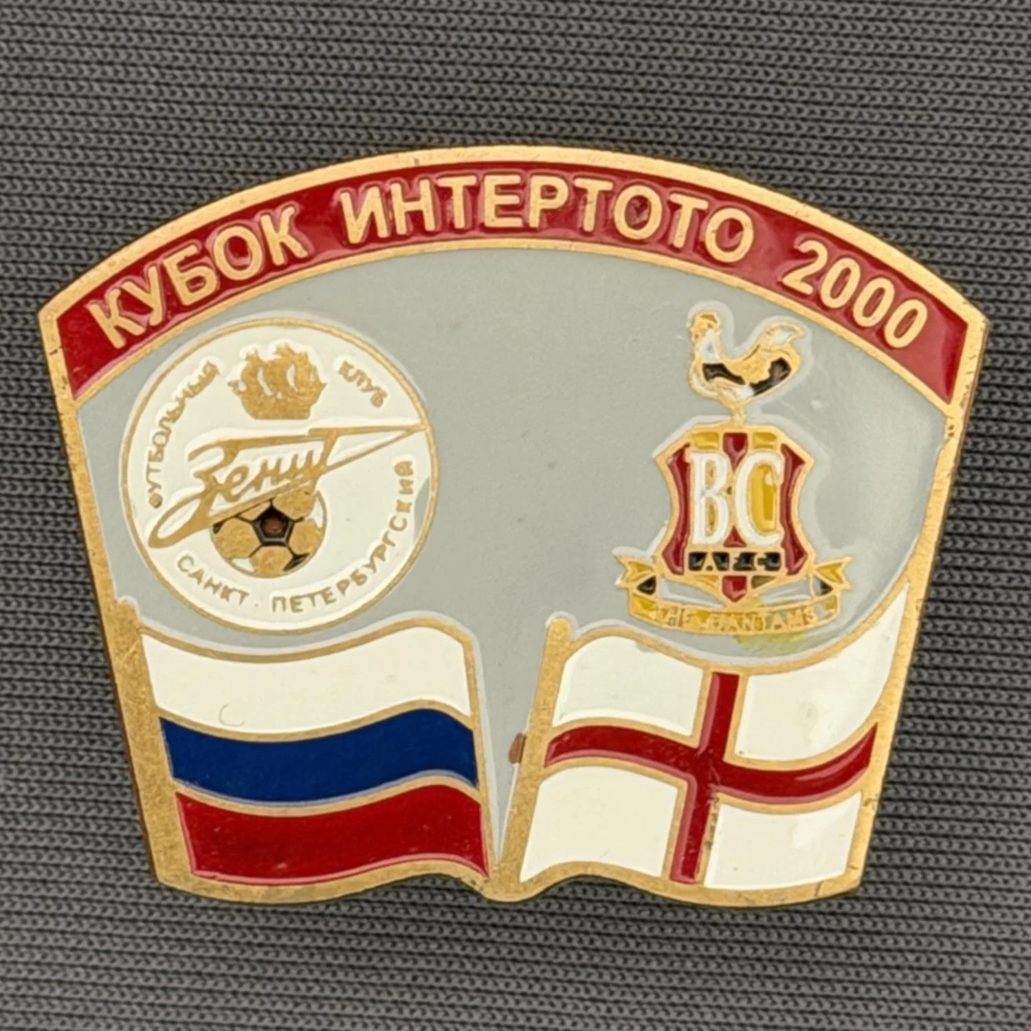 Reference Number: BCRUS029
Size: H 26 mm x W 32.3 mm
Pin Type: Metal Clutch
Plating: Antique Gold
Value: £12
Manufacturer: Unknown
Comments: Zenit St. Petersburg Inter Toto Cup, Red Top, Grey Background