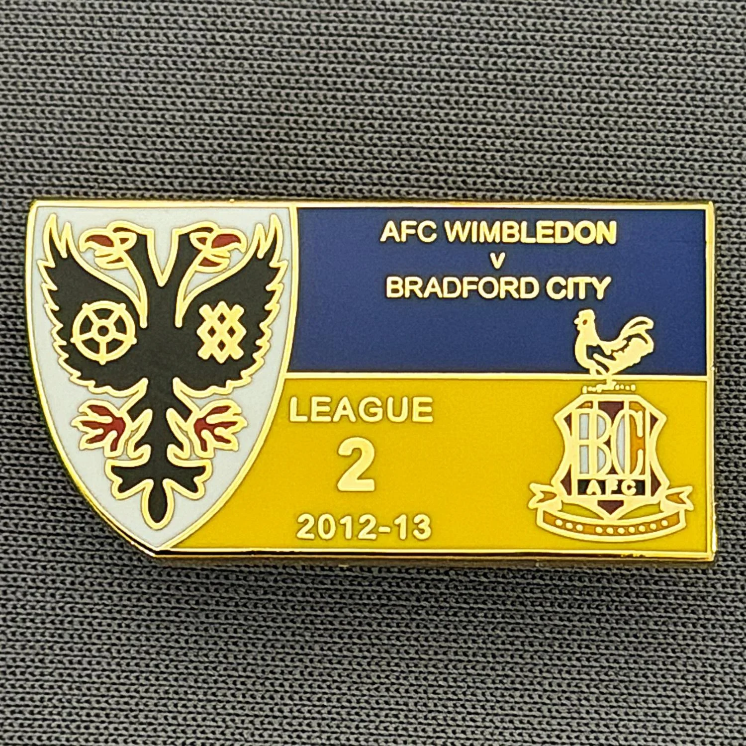 Reference Number: BCOFIX111
Size: H 15.2 mm x W 28.6 mm
Pin Type: Brooch Pin
Plating: Gold
Value: £5
Manufacturer: Terry's Badges
Comments: A.F.C. Wimbledon v Bradford City, League Two 2012/13 