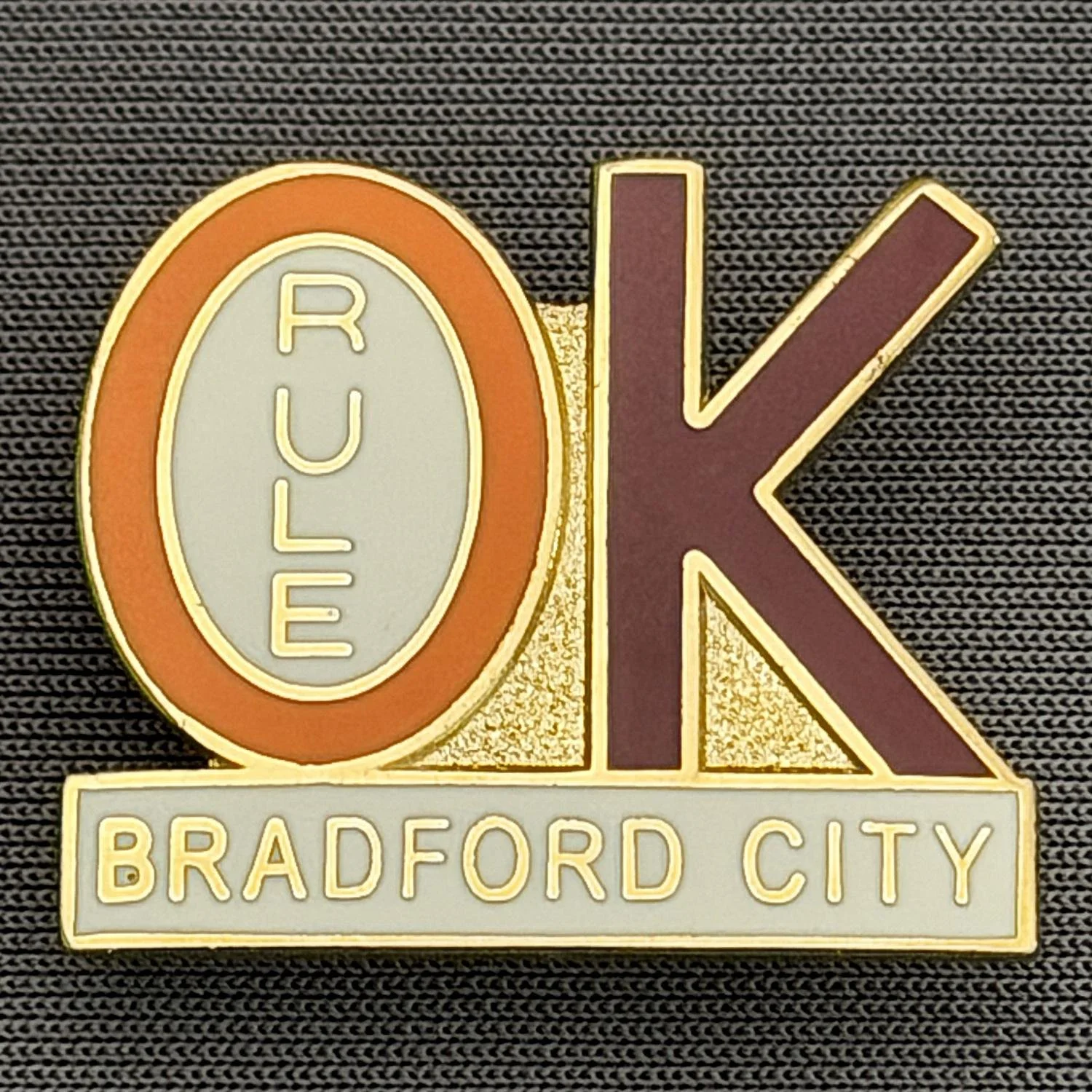 Reference Number: BCBCFC047
Size: H 21.7 mm x W 25.3 mm
Pin Type: Brooch Pin
Plating: Gold
Value: £6
Manufacturer: Paraders
Comments: Bradford City Rule OK, Amber & Claret, Copy of Original Version