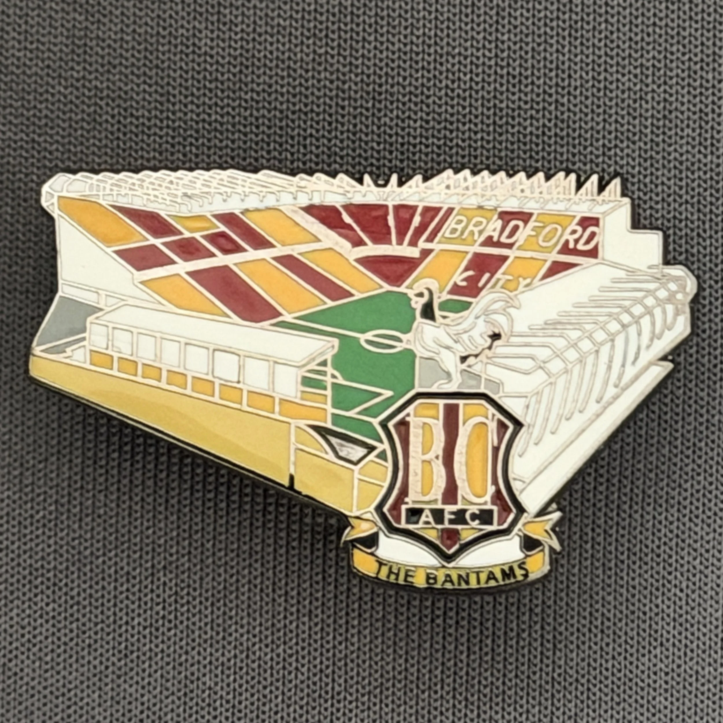 Reference Number: BCVP021
Size: H 20.5 mm x W 32.1 mm
Pin Type: Metal Clutch
Plating: Nickel
Value: £4
Manufacturer: Dan Lloyd
Comments: Valley Parade Stadium with Coloured City Logo
