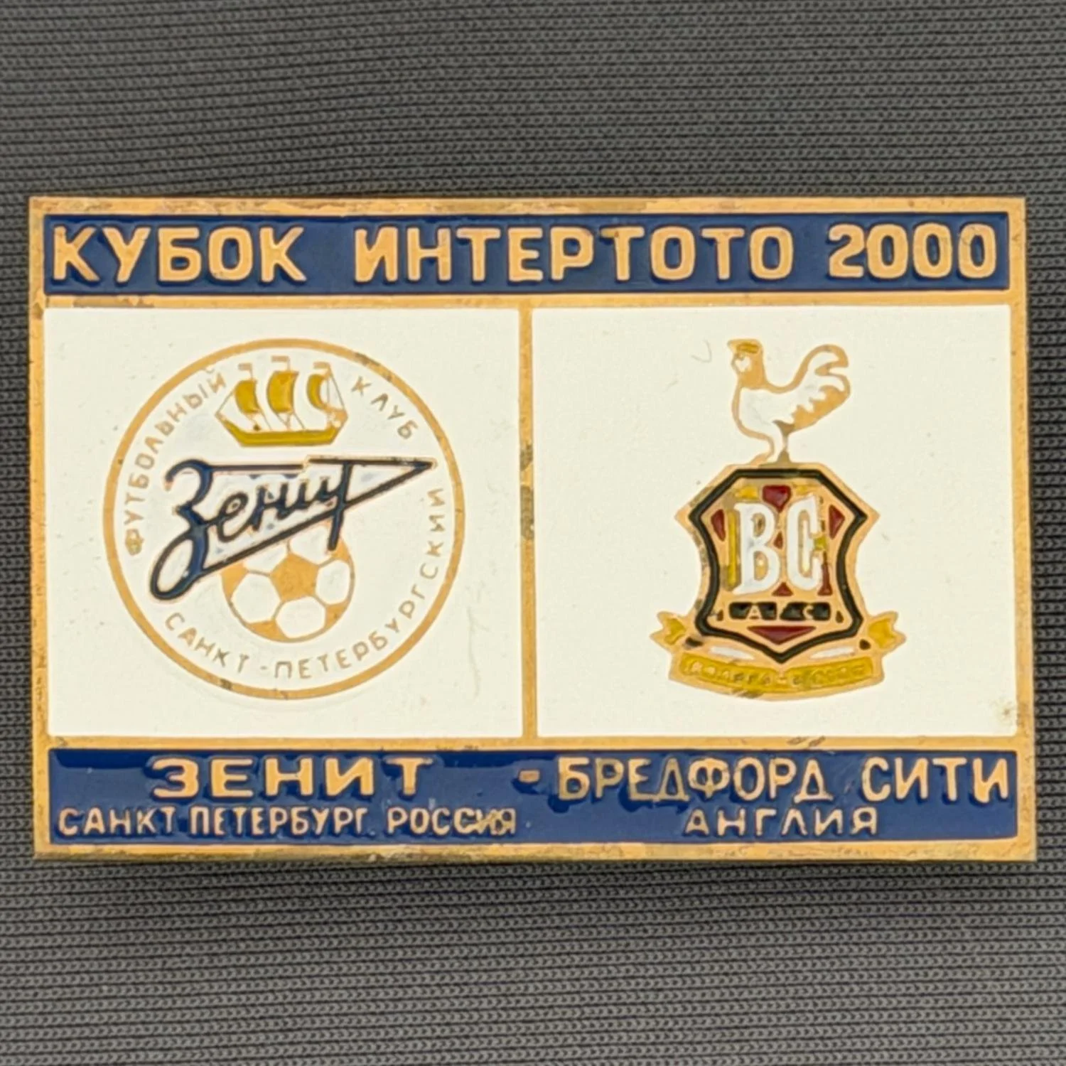 Reference Number: BCRUS015
Size: H 29.6 mm x W 44.6 mm
Pin Type: Metal Clutch
Plating: Antique Gold
Value: £12
Manufacturer: Unknown
Comments: Zenit St. Petersburg Inter Toto Cup, Blue Top, White Middle, Blue Bottom