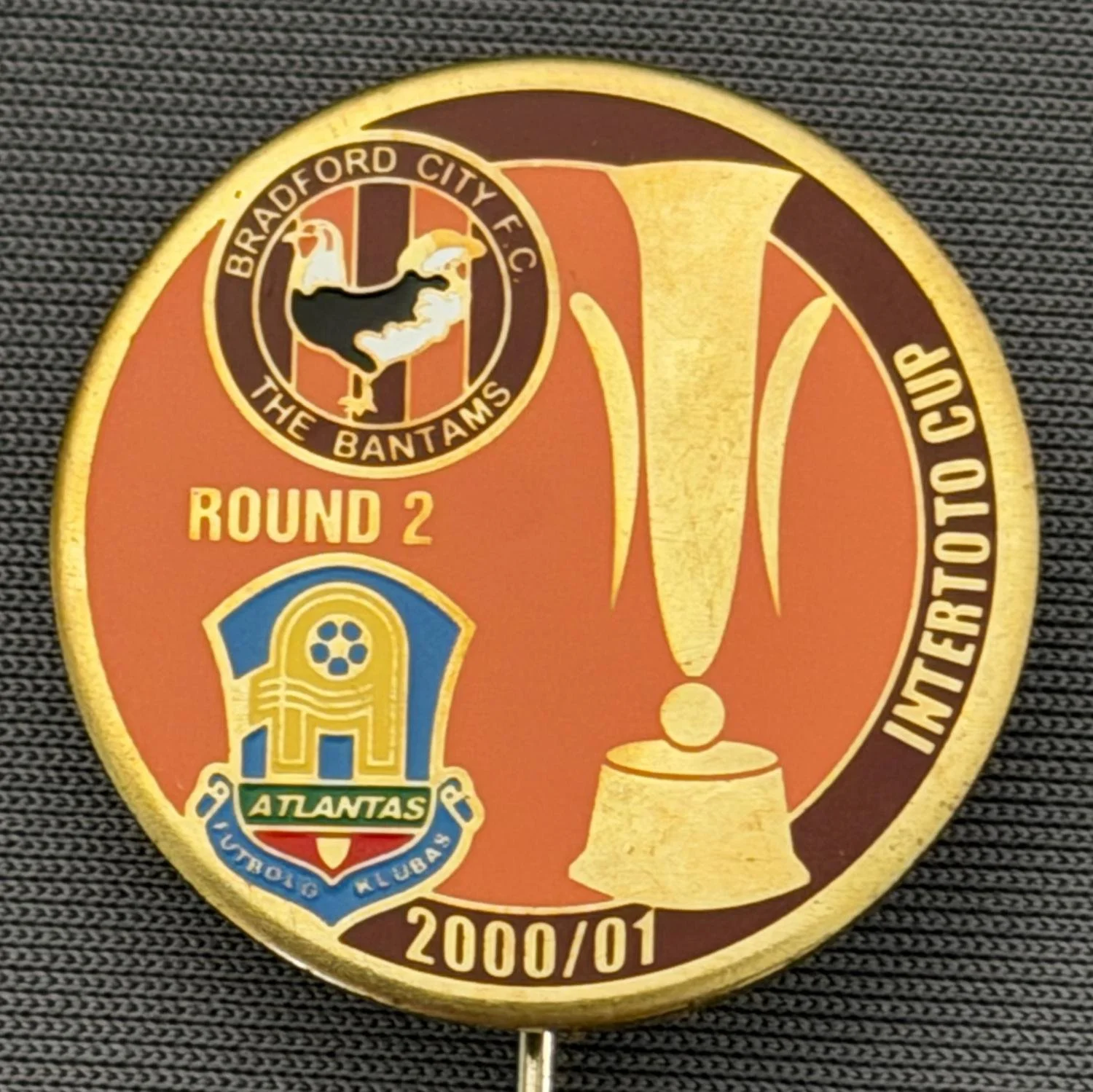 Reference Number: BCRUS040
Size: D 25 mm 
Pin Type: Metal Stick Pin
Plating: Gold
Value: £12
Manufacturer: Unknown
Comments: FK Atlantas Inter Toto Cup, City Logo, Amber & Claret Version