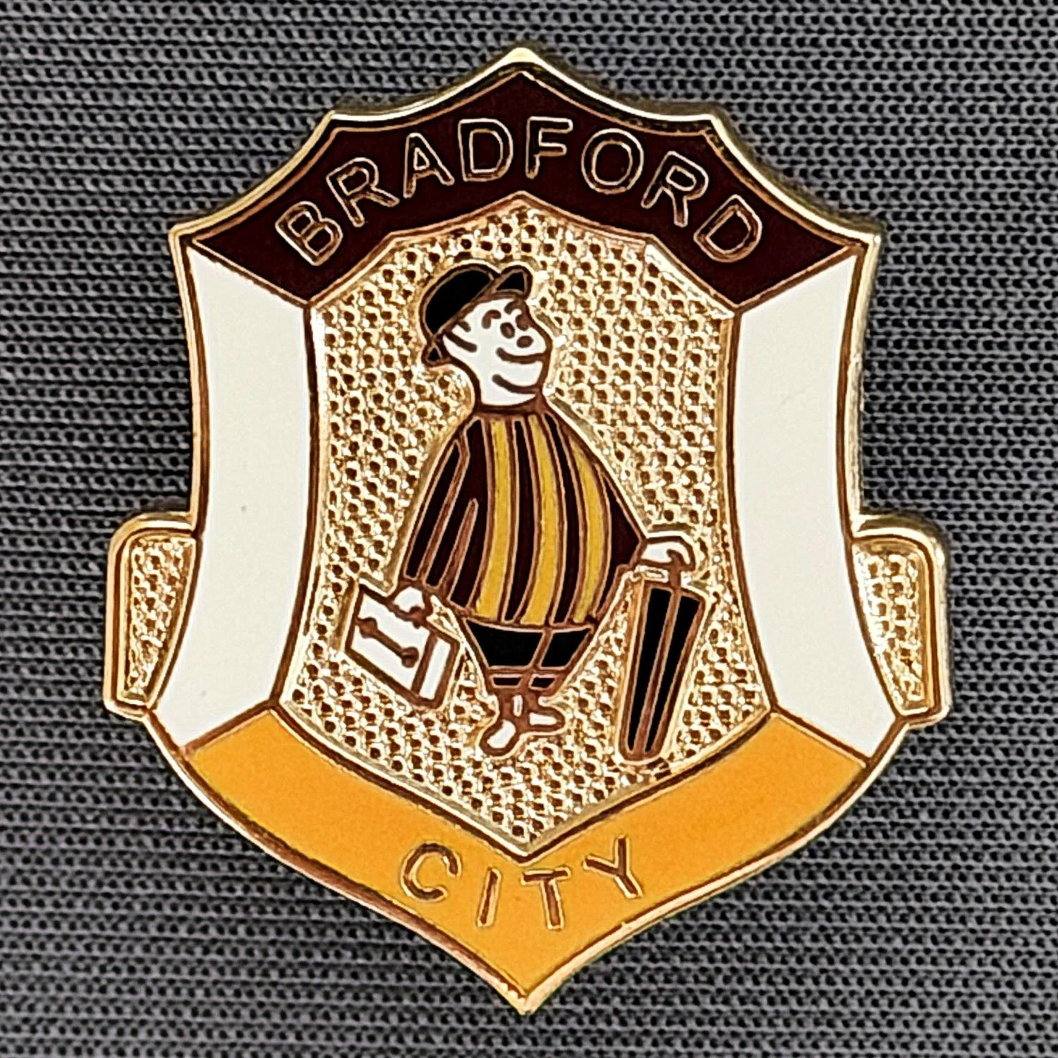 Reference Number: BCGEN047
Size: H 26.1 mm x W 22.4 mm
Pin Type: Plastic Clutch
Plating: Gold
Value: £8
Manufacturer: Andy Stokes
Comments: Black, White & Amber City Gent Shield