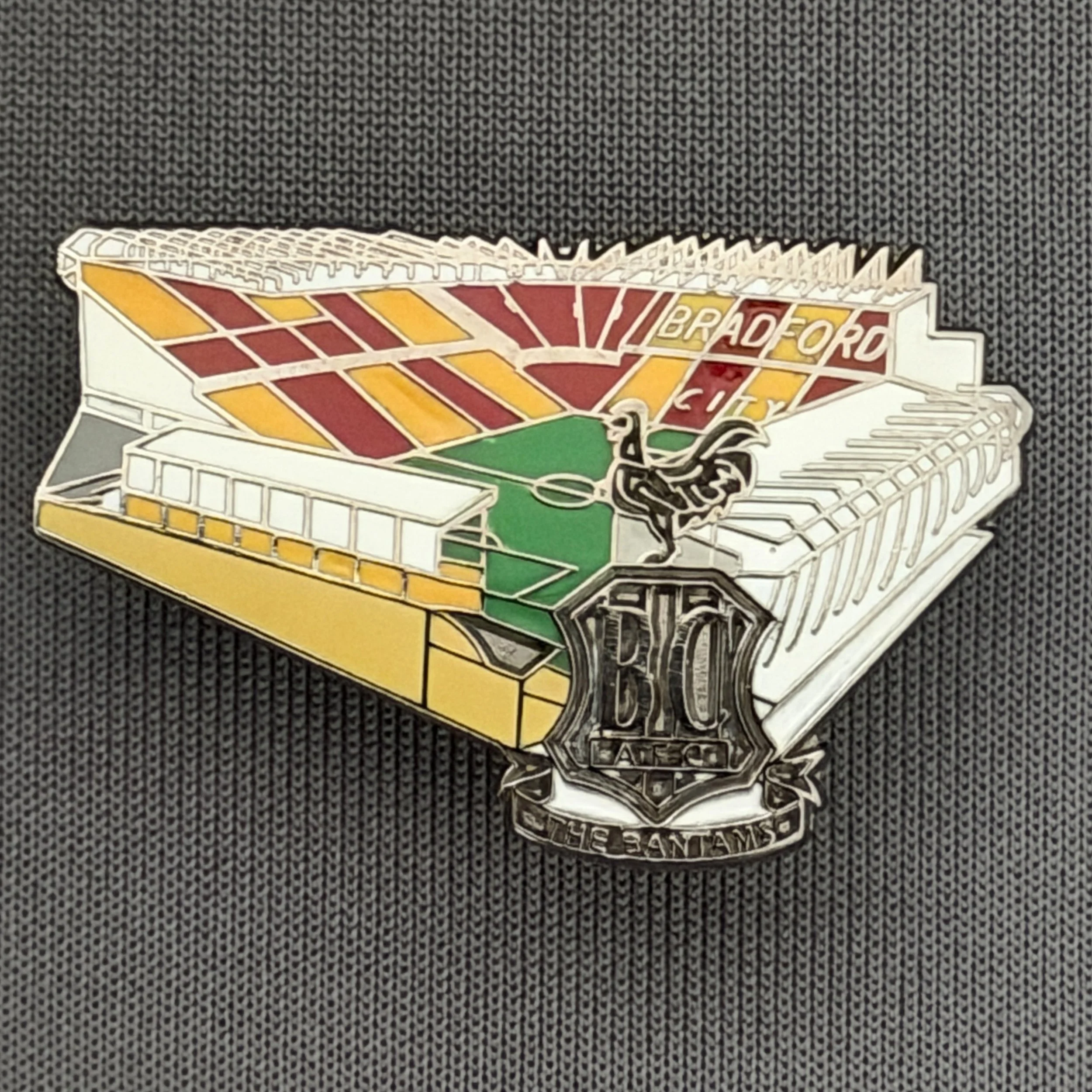 Reference Number: BCVP024
Size: H 20.5 mm x W 32.1 mm
Pin Type: Metal Clutch
Plating: Black Nickel
Value: £4
Manufacturer: Dan Lloyd
Comments: Valley Parade Stadium with Metal City Logo