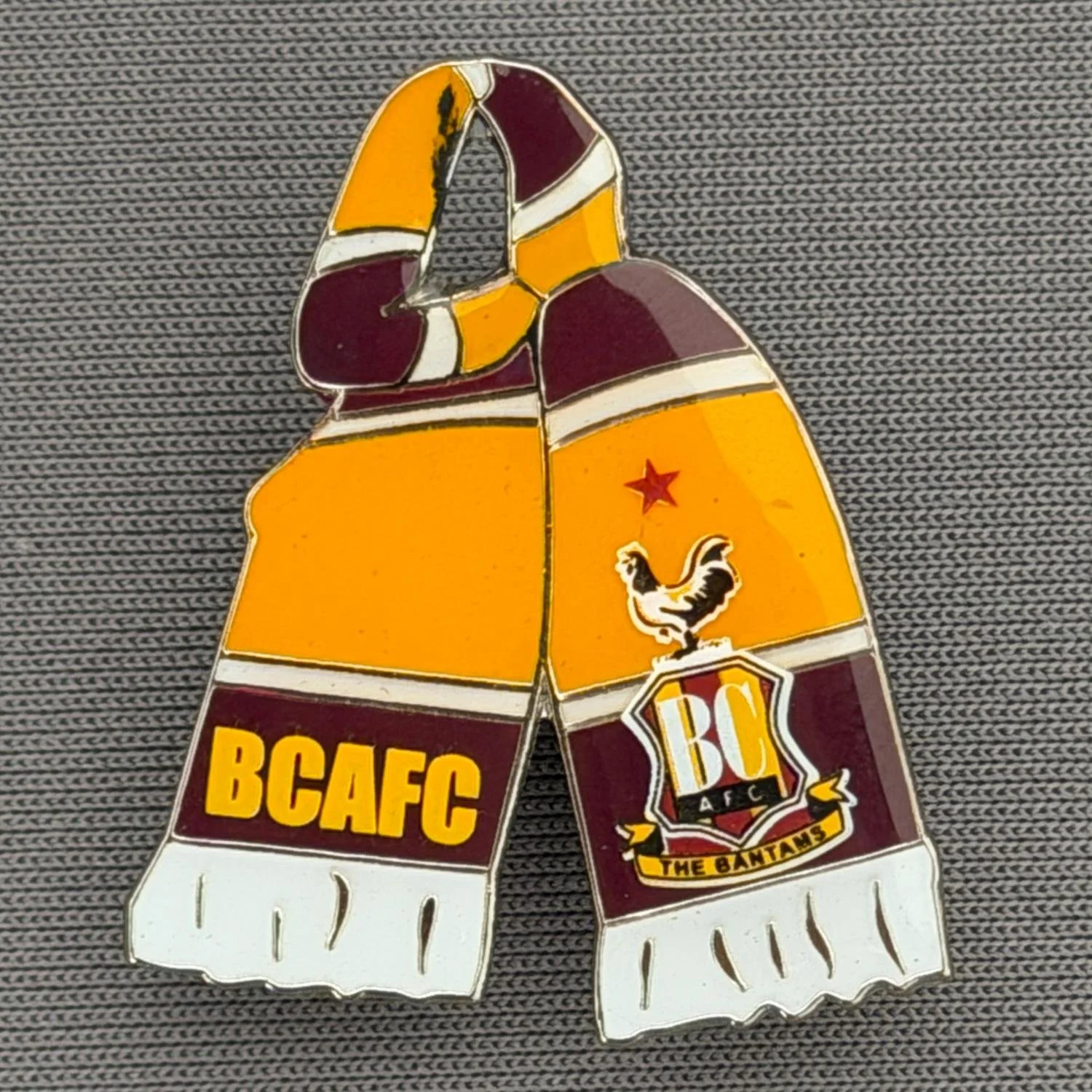 Reference Number: BCSCA007
Size: H 28.8 mm x W 23.9 mm
Pin Type: Metal Clutch
Plating: Silver
Value: £6
Manufacturer: Bradford City Shop
Comments: Claret & Amber Scarf with BCAFC & City Logo