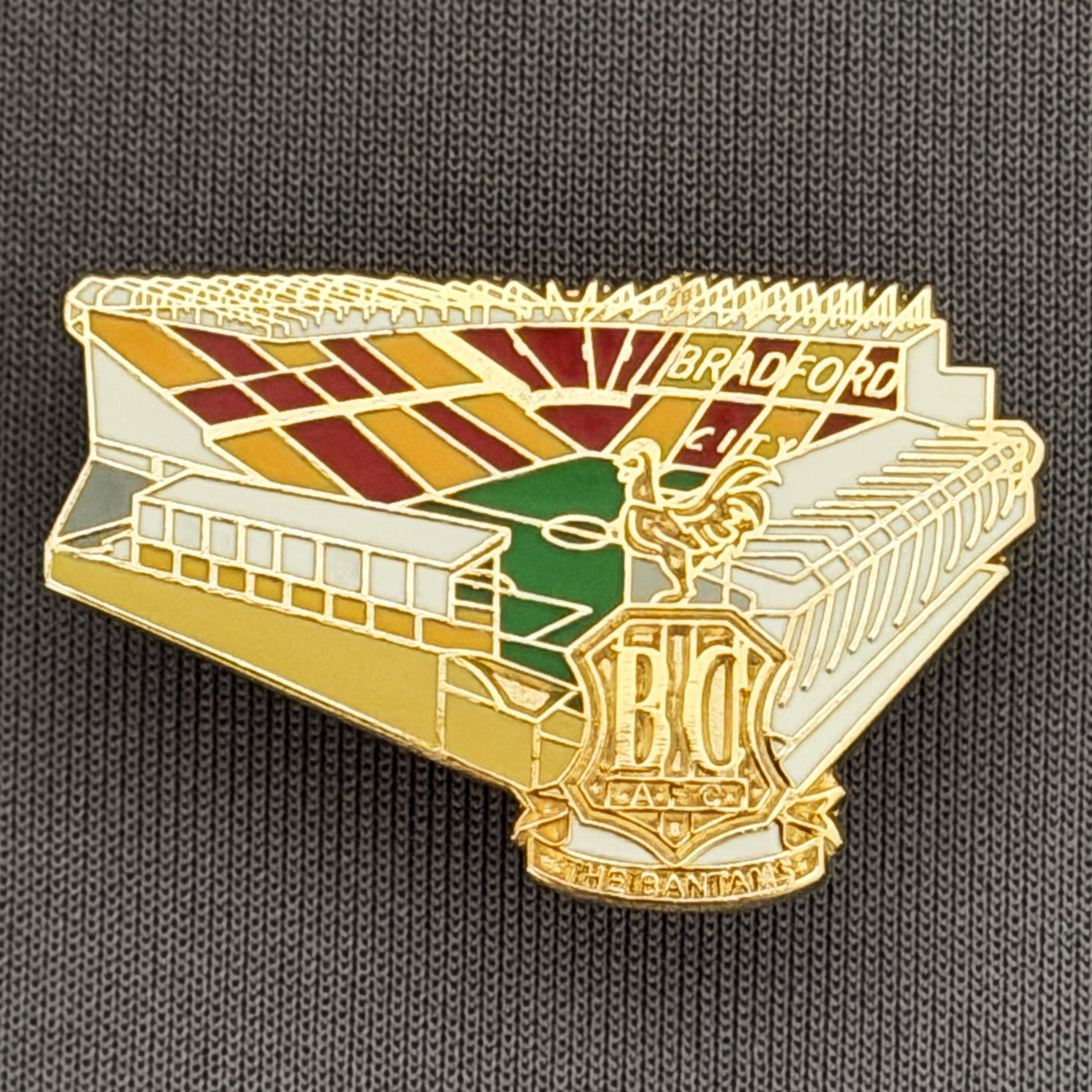Reference Number: BCVP020
Size: H 20.5 mm x W 32.1 mm
Pin Type: Metal Clutch
Plating: Gold
Value: £4
Manufacturer: Dan Lloyd
Comments: Valley Parade Stadium with Metal City Logo