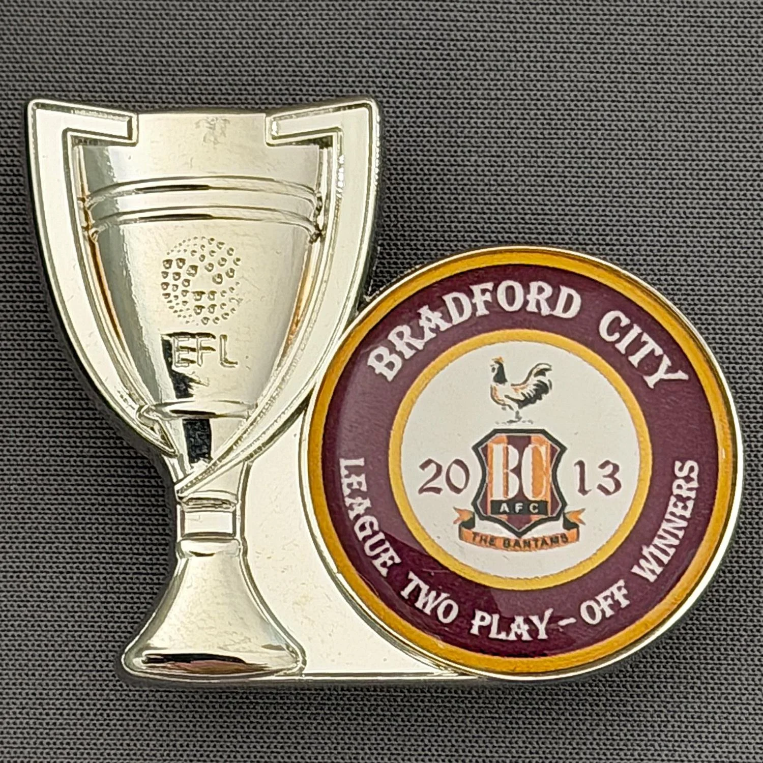 Reference Number: BCEVE81
Size: H 35.7 mm x W 46.2 mm
Pin Type: Double Rubber Clutch
Plating: Silver
Value: £8
Manufacturer: Craig Weatherer
Comments: League 2 Play Off Winners 2013, Metal Cup, Plastic Insert
