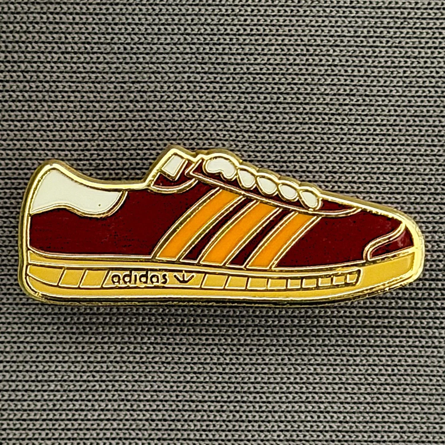 Reference Number: BCUN045
Size: H 9.9 mm x W 24.8 mm
Pin Type: Brooch Pin
Plating: Gold
Value: £4
Manufacturer: Unknown
Comments: Claret, Amber & White Trainer, Small Version