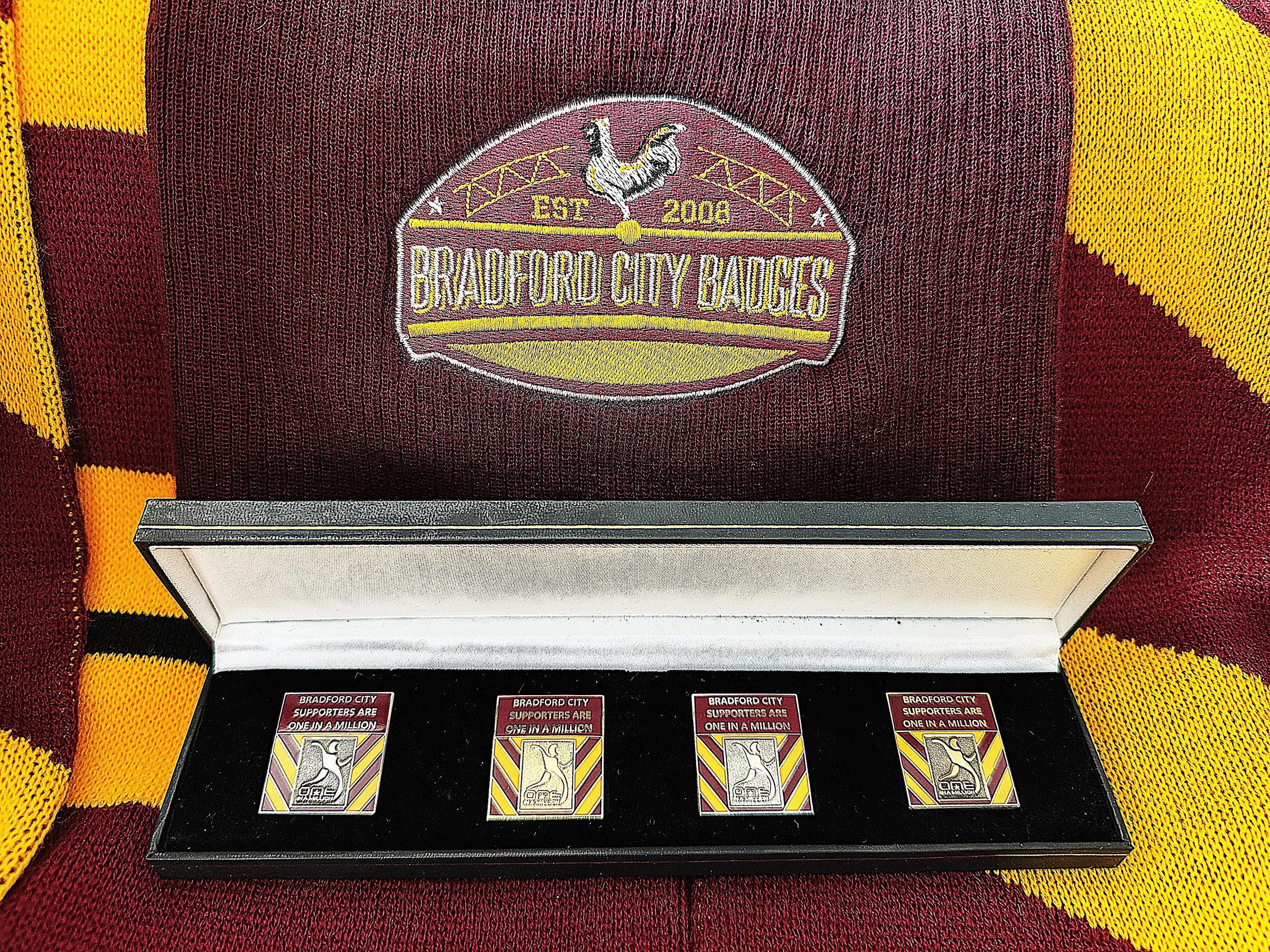 Bradford City supporters display city and support memorabilia, with an embroidered badge featuring a rooster, the club name, establishment date of 2008, and supportive messages.