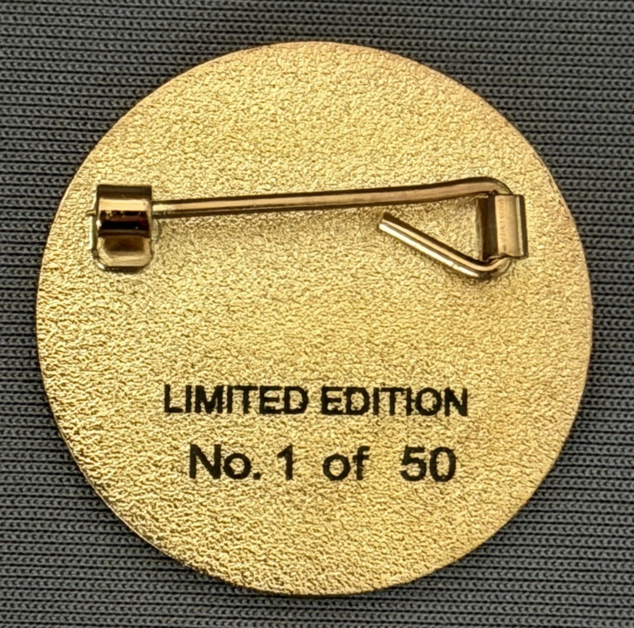 Gold-colored badge with a pin on the back, engraved with the text "Limited Edition No. 1 of 50."