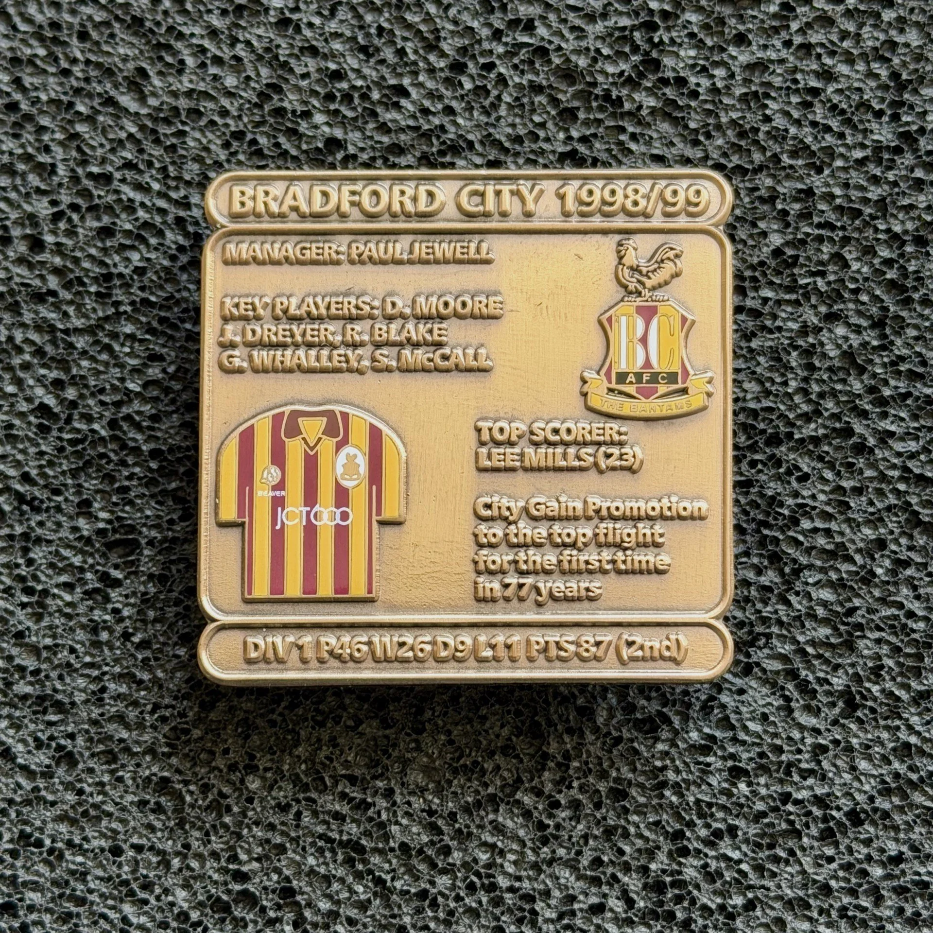 Plaque commemorating Bradford City football team 1998/99 with manager Paul Jewell, key players including D. Moore, G. Black, G. Whelan, S. McCall, and top scorer Lee Mills. Features Bradford City badge and a depiction of a lion.