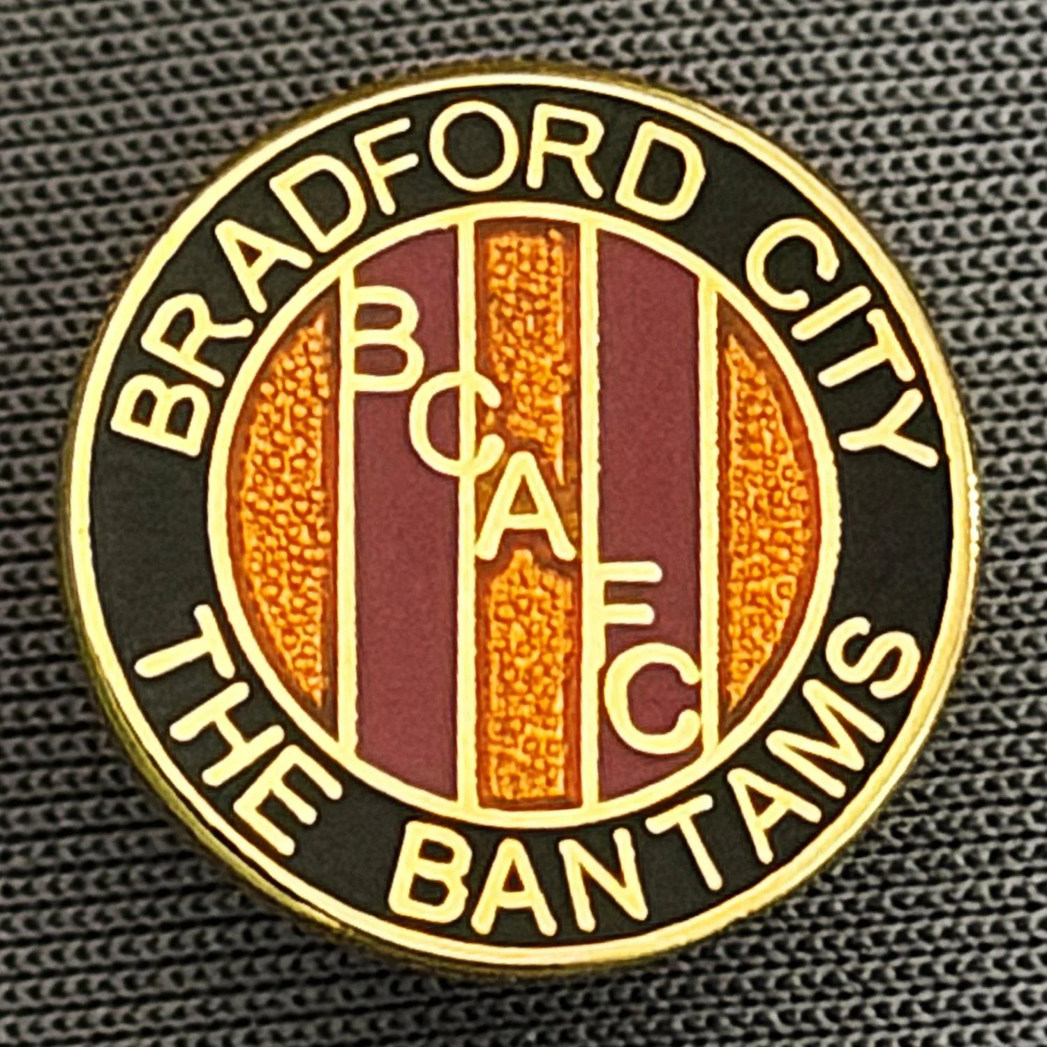 Reference Number: BCBCFC018
Size: D 15 mm
Pin Type: Metal Clutch
Plating: Gold
Value: £6
Manufacturer: Andy Stokes
Comments: Bradford City, BCAFC, The Bantams, Black, Claret & Amber Version