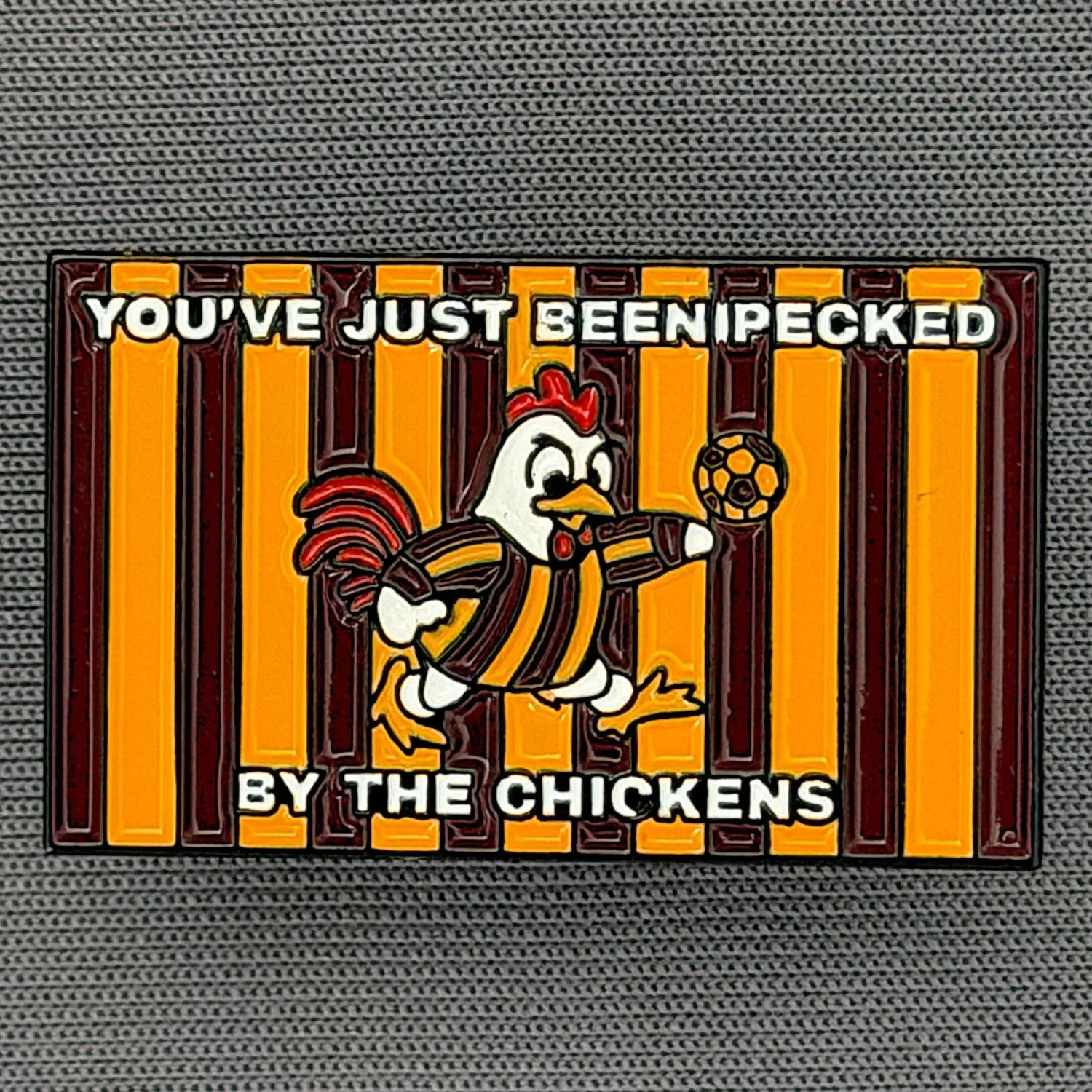 Reference Number: BCBAN069
Size: H 18.4 mm x W 30.5 mm
Pin Type: Metal Clutch
Plating: Black Nickel
Value: £6
Manufacturer: Bingley Bantams
Comments: Just BeenIPecked By The Chickens (Bizarre Badge Mould Imperfection)