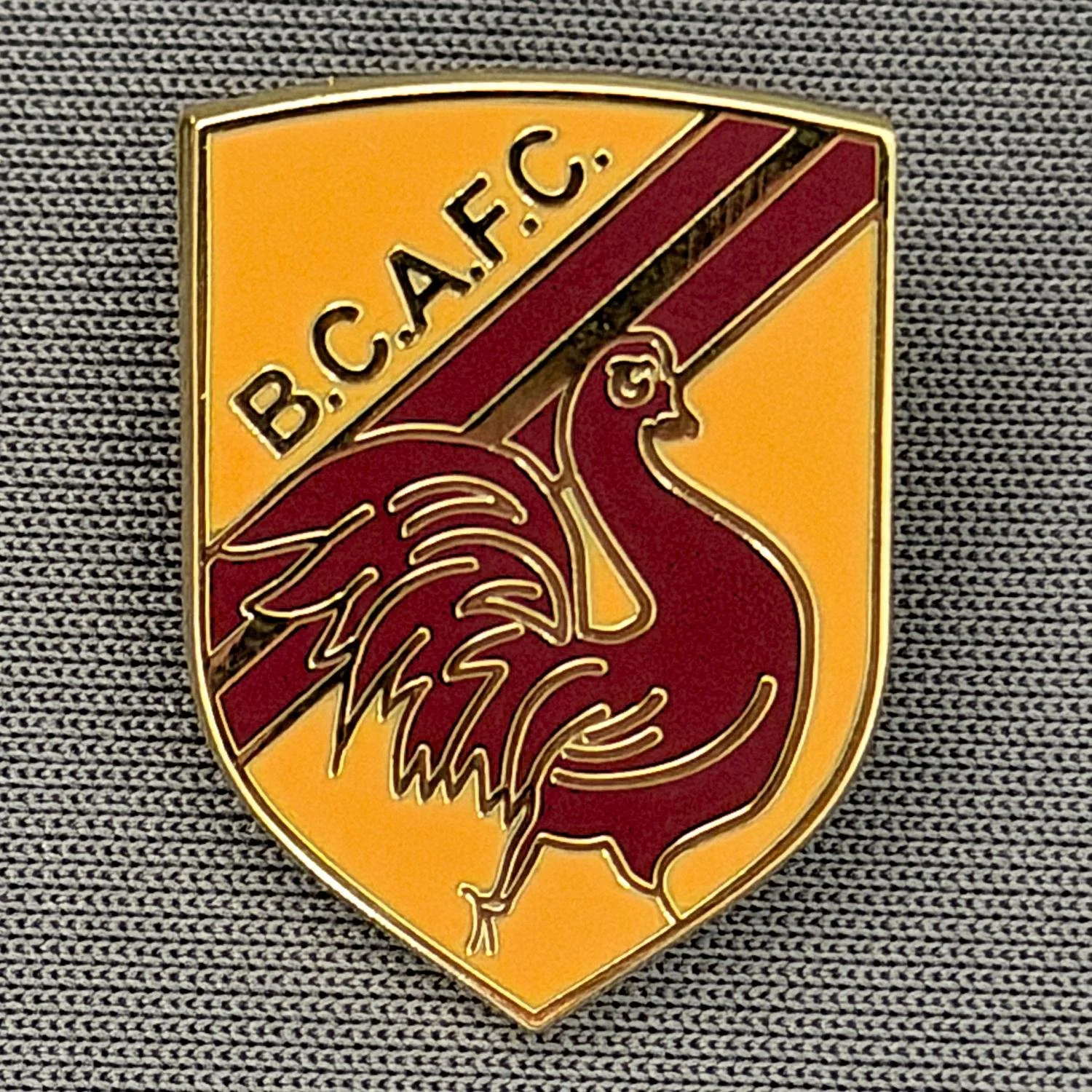 Reference Number: BCBAN051
Size: H 22.9 mm x W 16.8 mm
Pin Type: Brooch Pin
Plating: Gold
Value: £6
Manufacturer: Unknown
Comments: Amber & Claret Bantam Shield, Small Version 