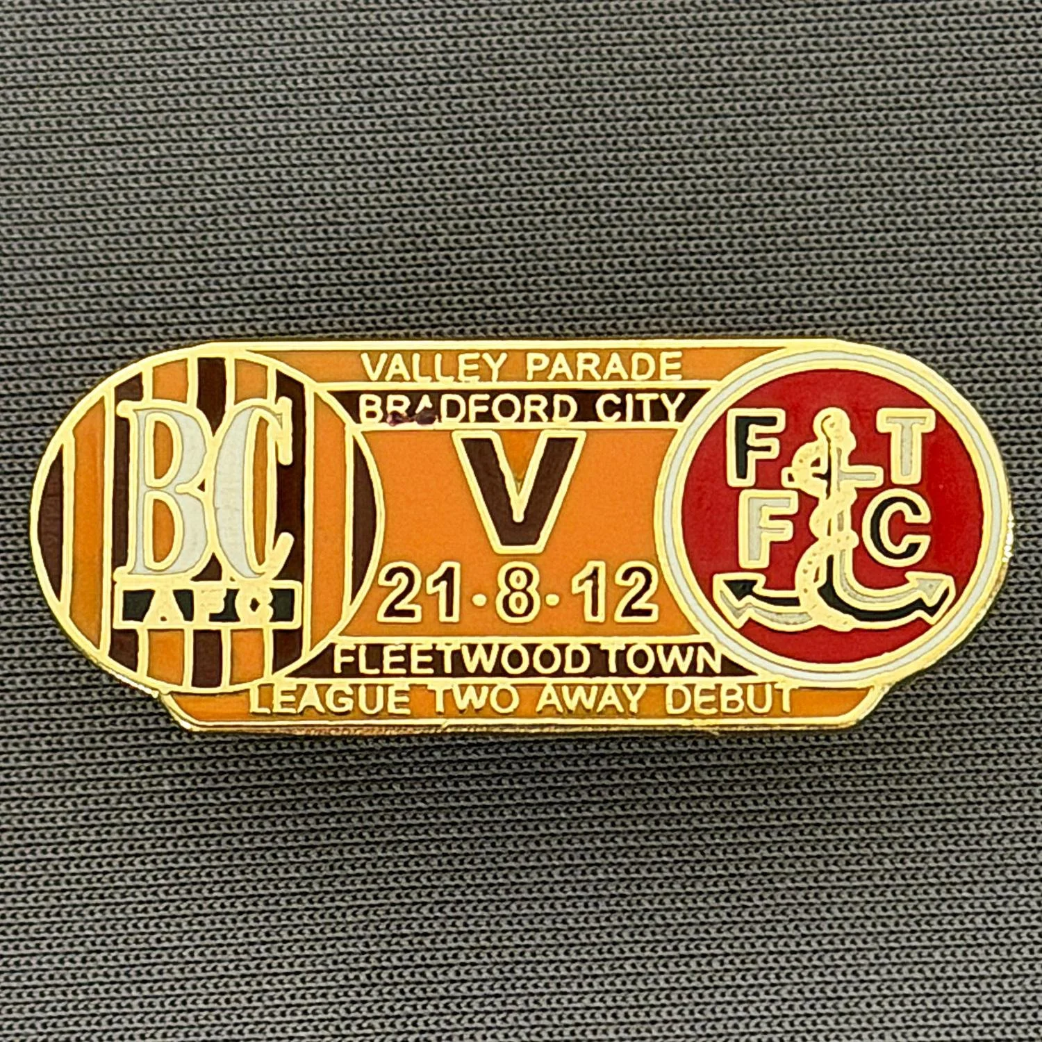 Reference Number: BCOFIX131
Size: H 14.4 mm x W 35.1 mm
Pin Type: Double Rubber Clutch
Plating: Gold
Value: £5
Manufacturer: Unknown
Comments: Bradford City v Fleetwood Town 2012 League Two Debut, Amber & Claret  Version 