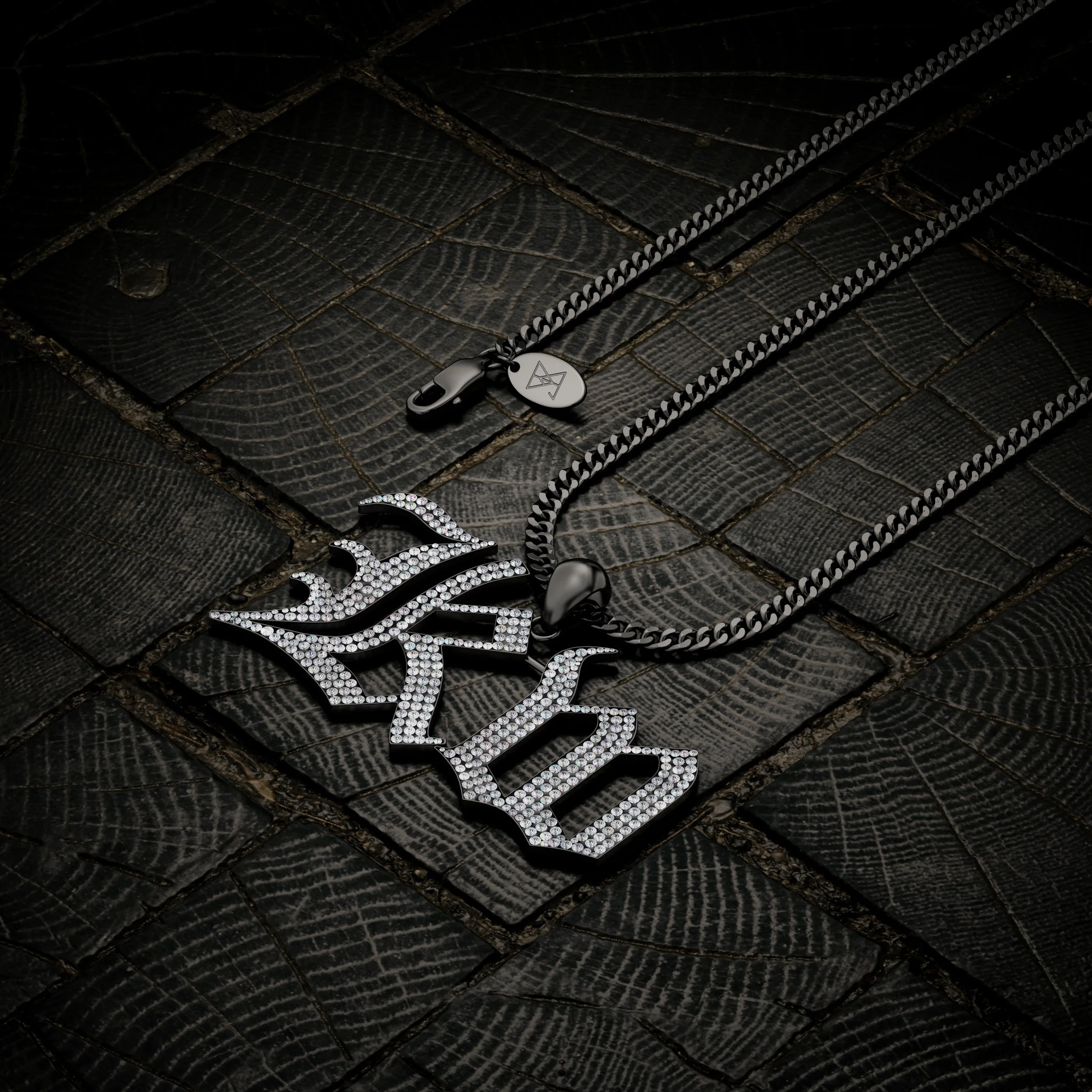 A silver chain necklace with a pendant spelling 'DONT' in large, crystal-studded letters, resting on a dark textured wooden surface.