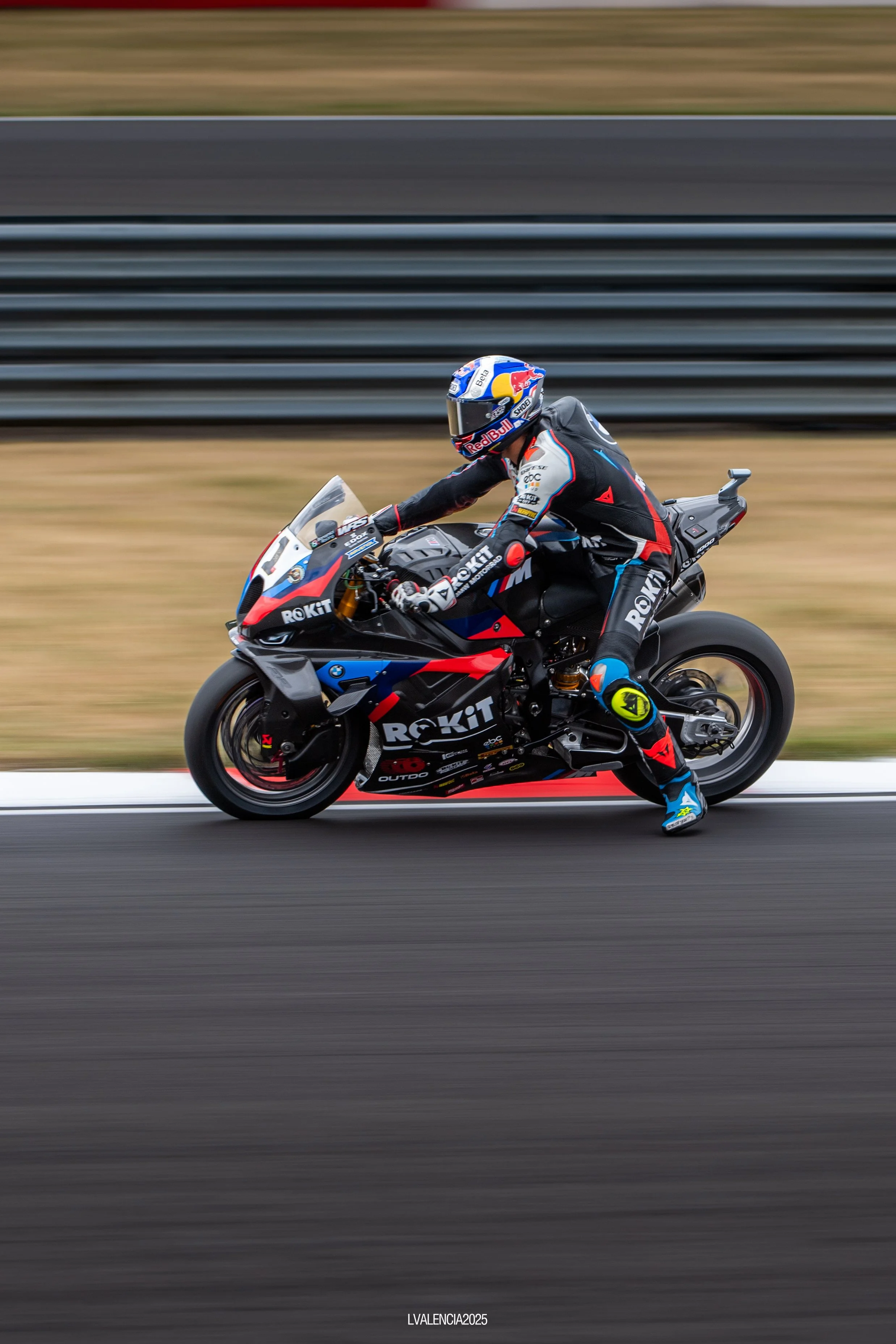 Motorcycle racer riding a race bike on a track, with motion blur in the background.