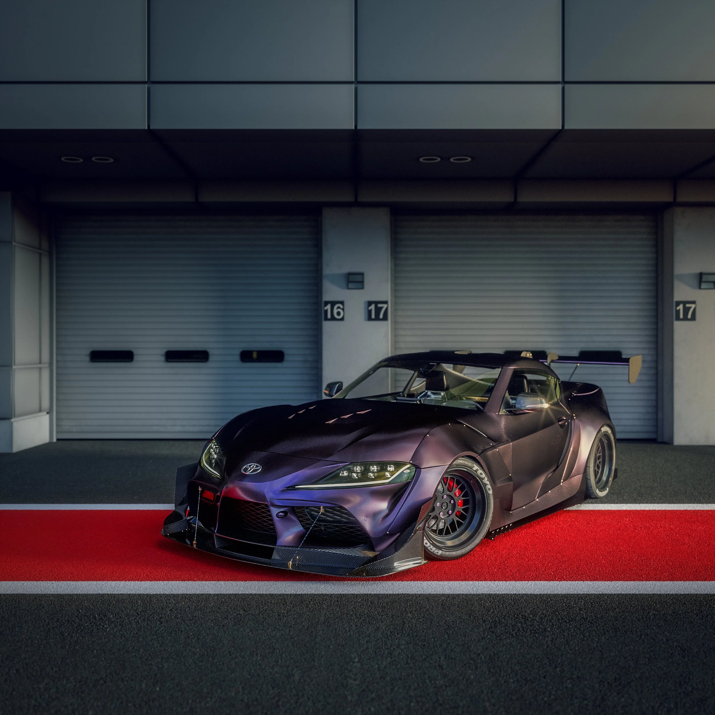 A black Toyota race car parked on a red strip in front of garage doors at a racing circuit.