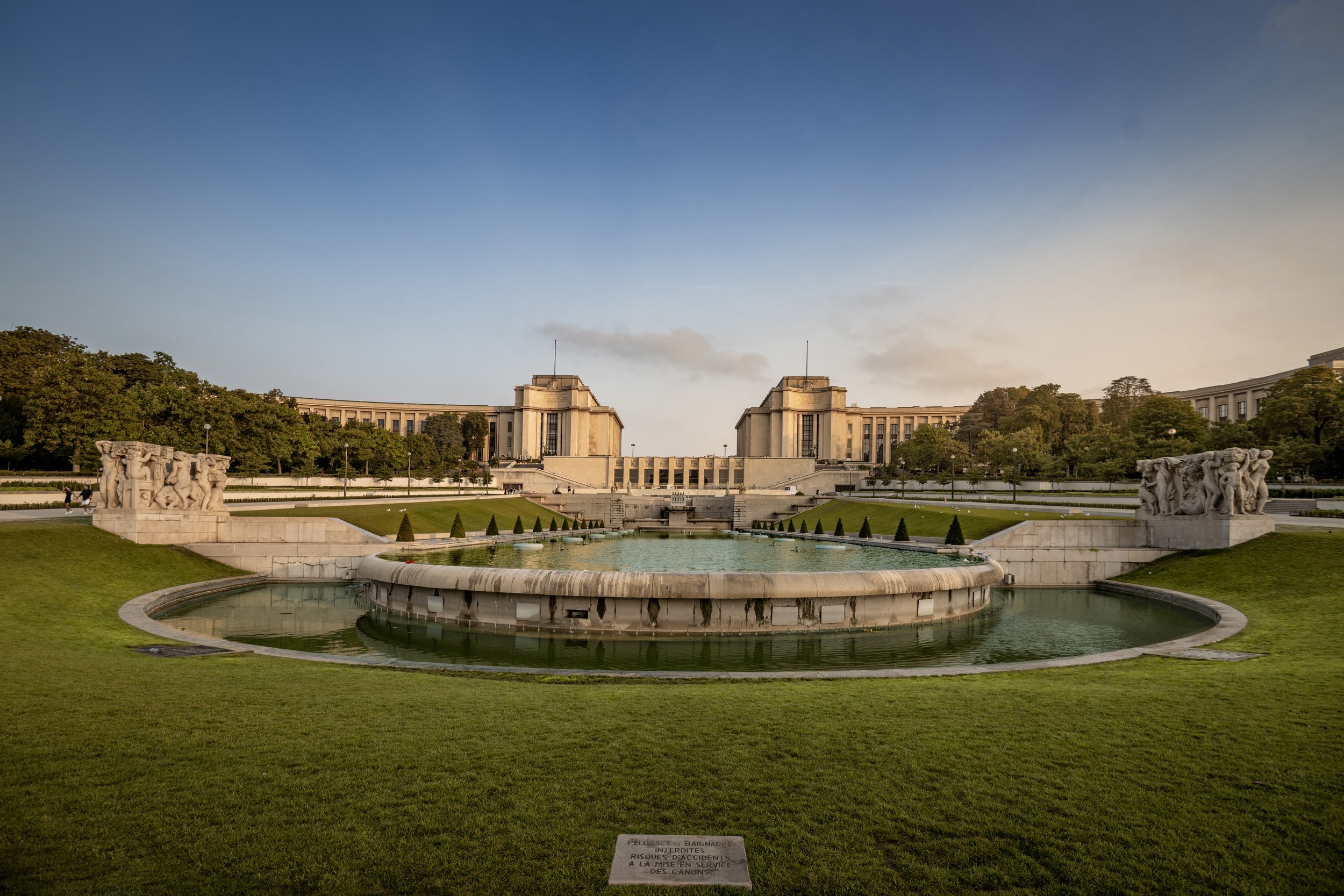 View of the Fountain of the World in the Parque de la Paz, with a grand building in the background, trees, and sculptures on either side of the fountain.