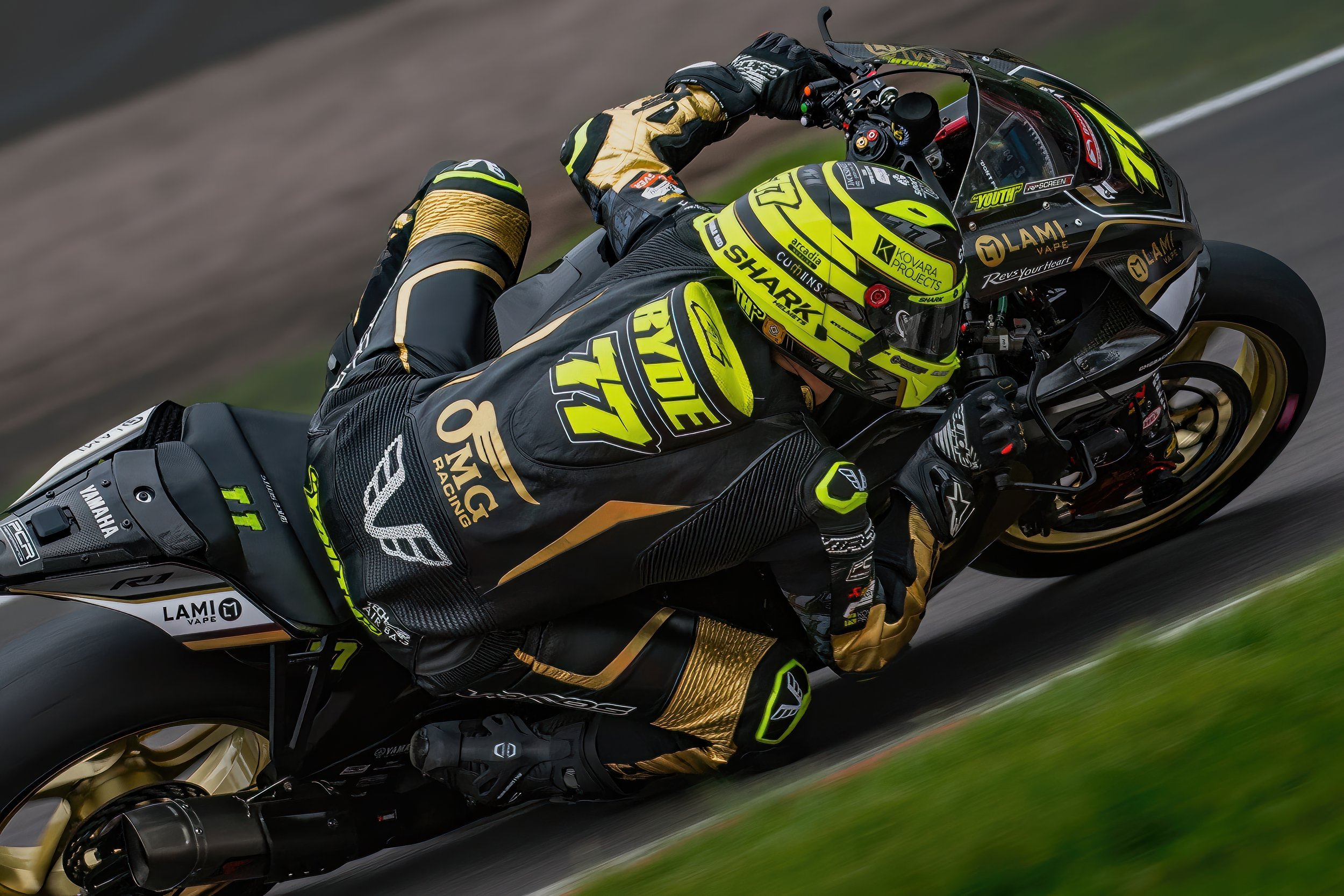 A motorcycle racer in black and yellow racing gear leaning into a turn on a race track.
