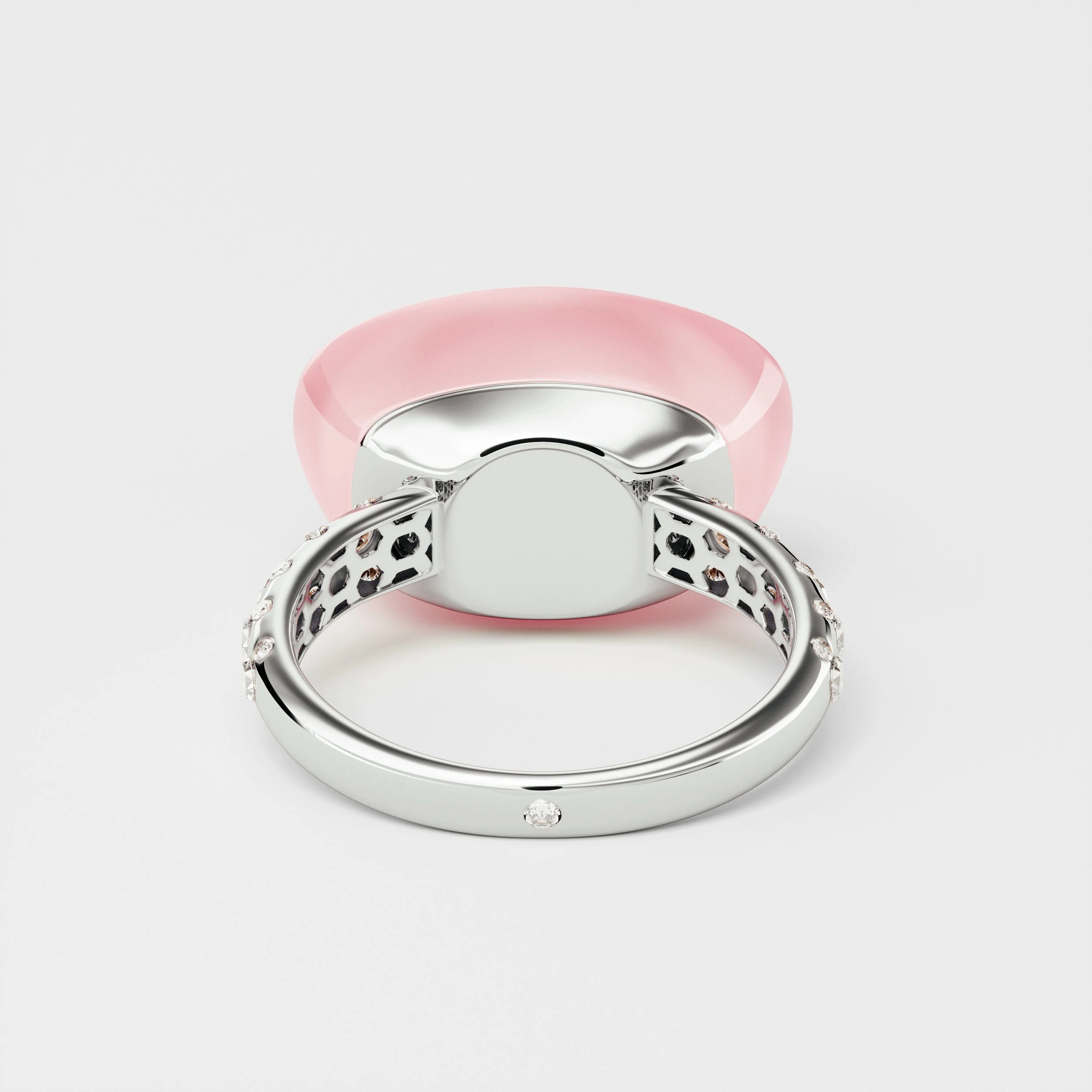 Close-up of a silver ring with diamonds seen from the bottom, with a pink object behind it.