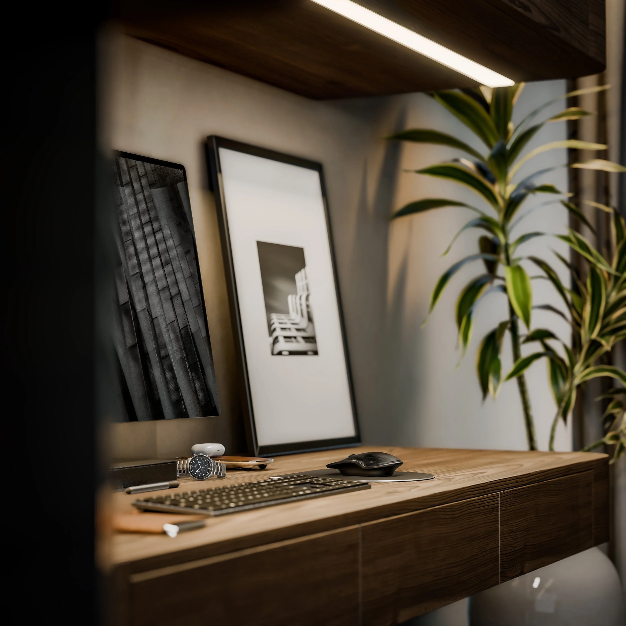A computer desk setup featuring a monitor, keyboard, and mouse, with framed black-and-white artwork, a watch, and potted plant on a wooden shelf in a professional office.