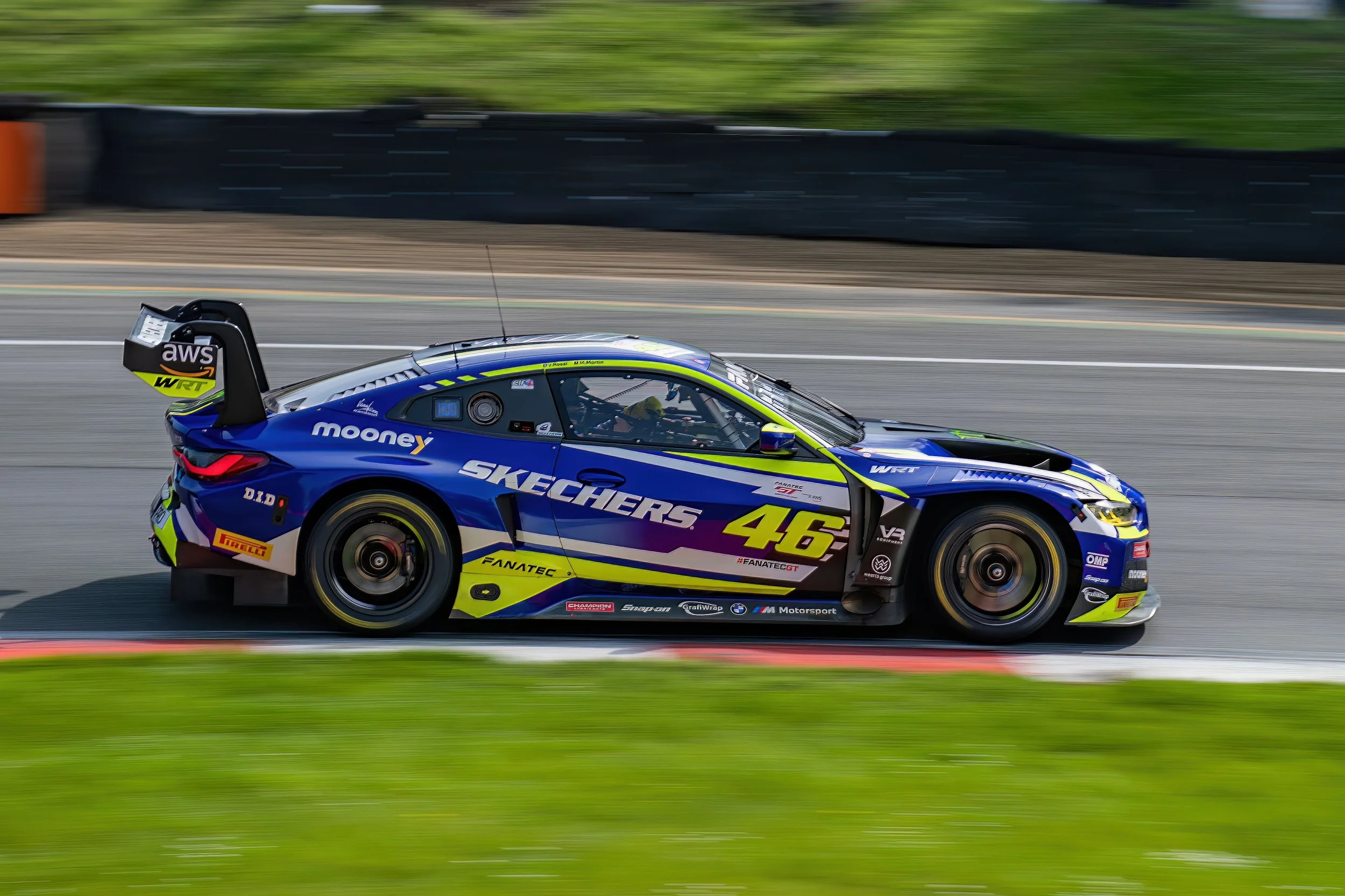 A blue race car with the number 46 on it speeding on a racetrack.