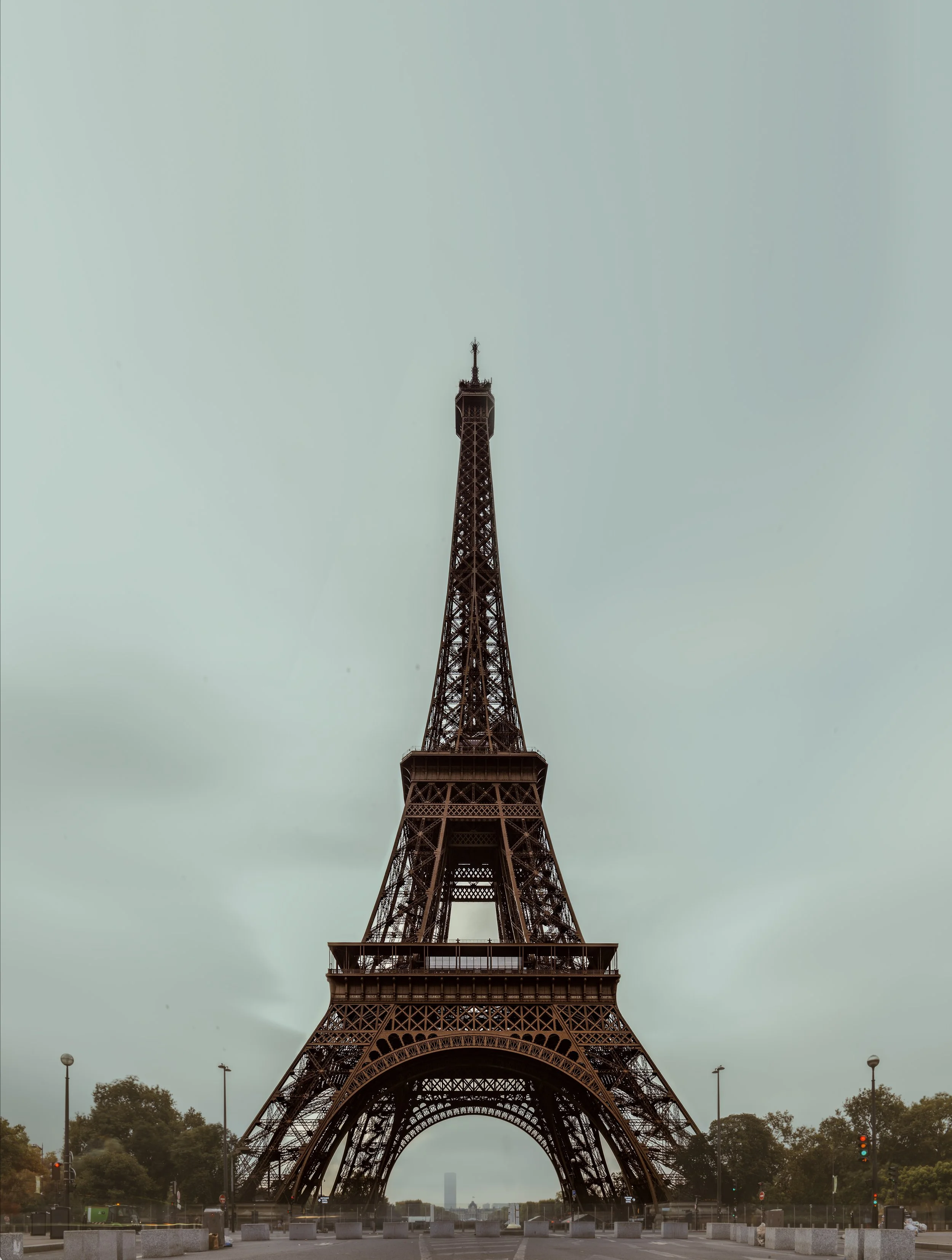 The Eiffel Tower viewed from the ground with an overcast sky in the background.