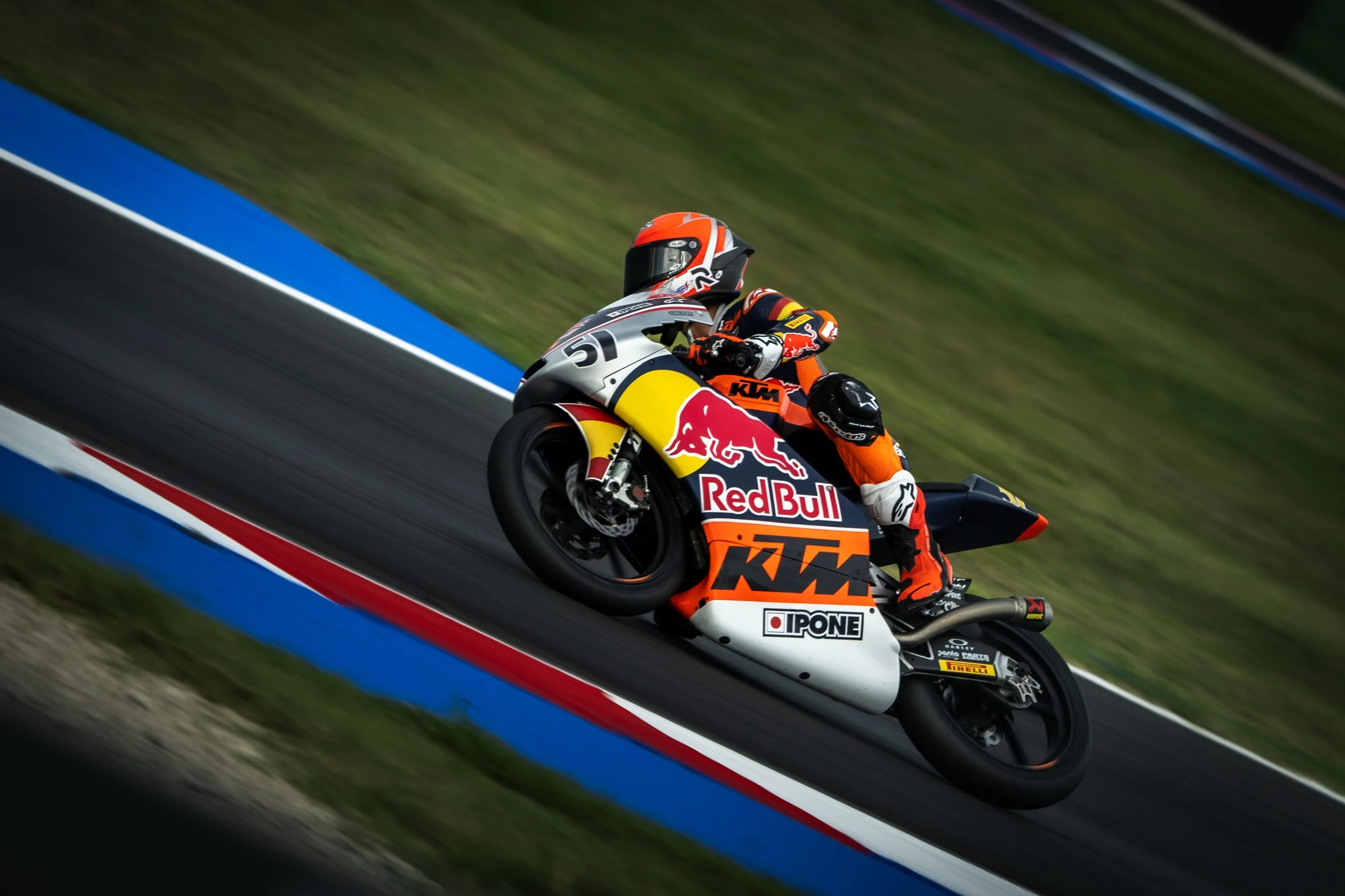 Motorcycle racer leaning into a turn on a race track with KTM and Red Bull branding