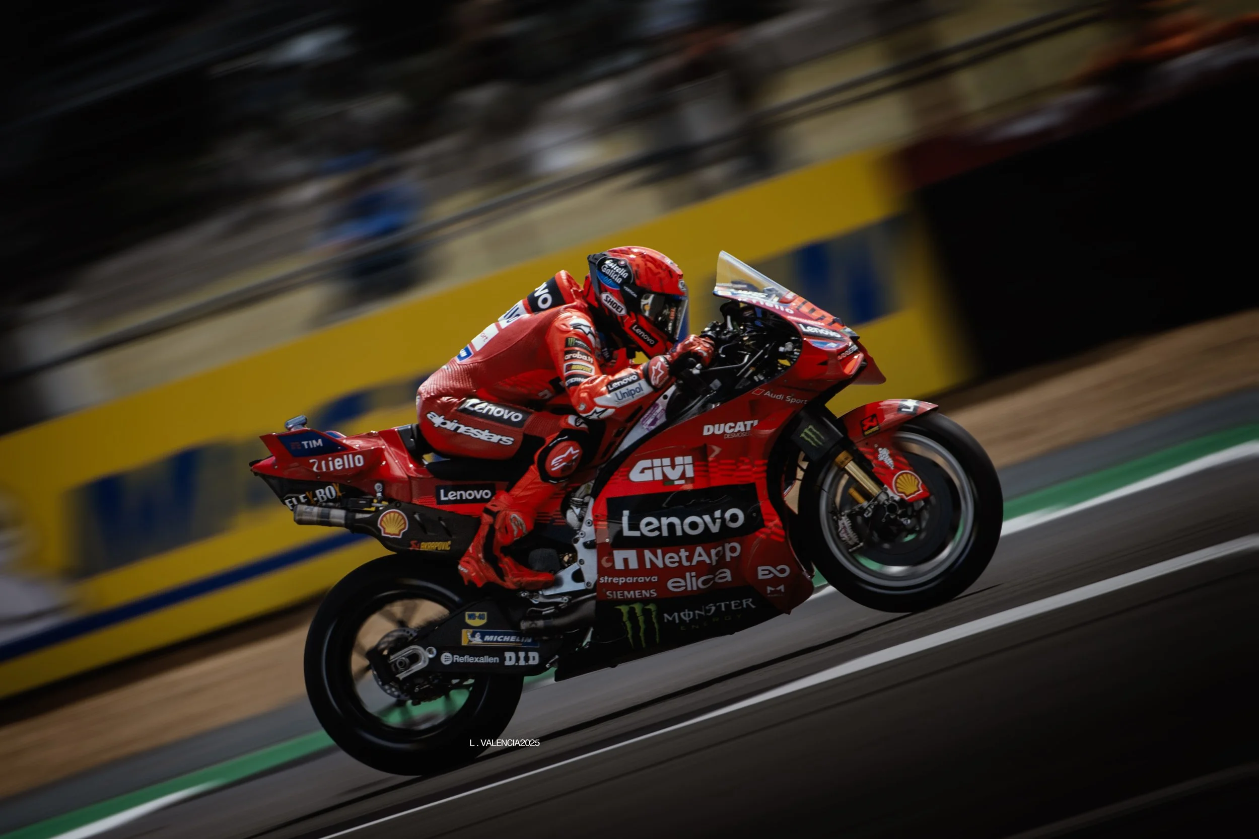 A motorcycle racer in a red suit riding a red Ducati bike during a race on a track