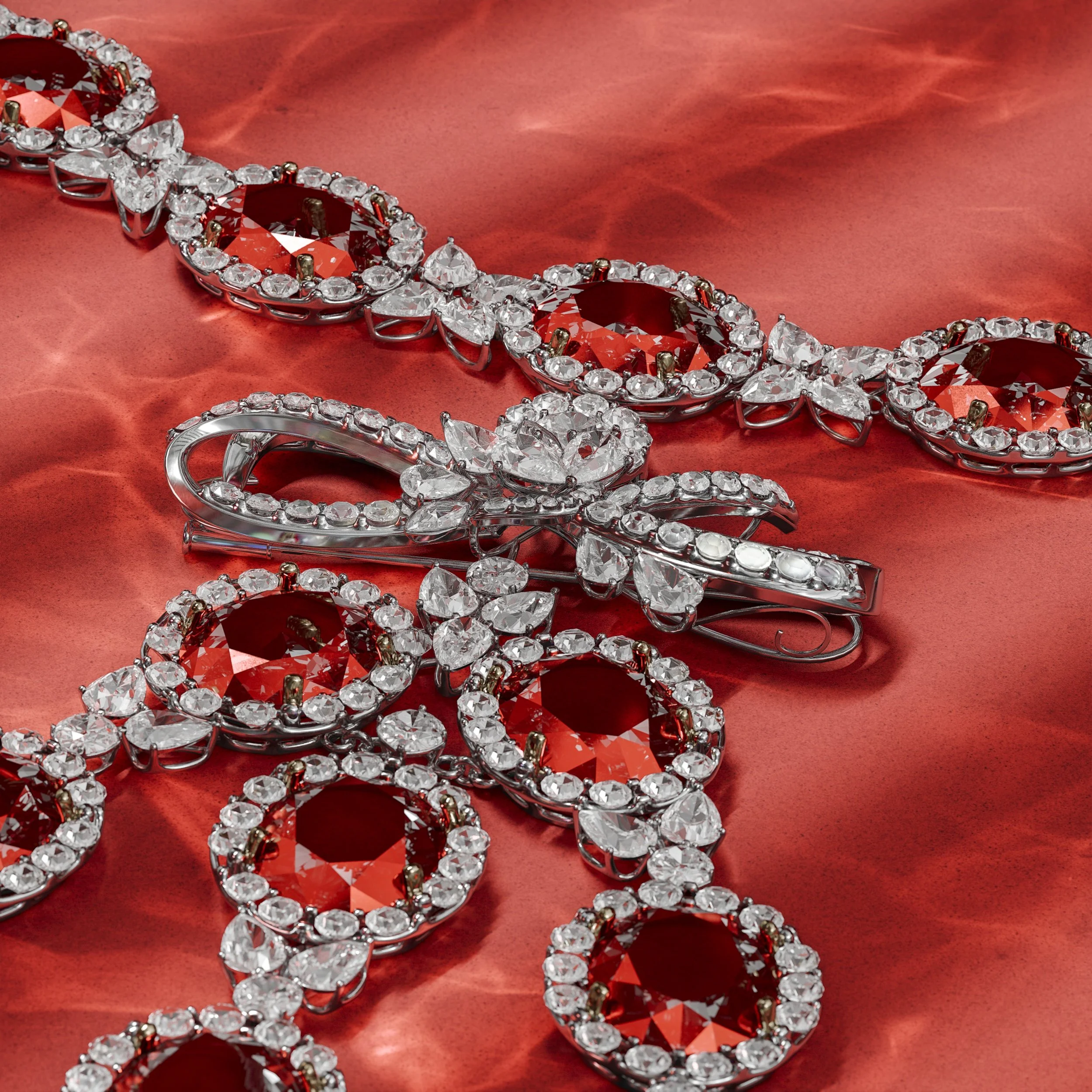 A jewelry piece with large red gemstones surrounded by clear, sparkling crystals, set in a silver-colored metal, lying on red satin fabric.