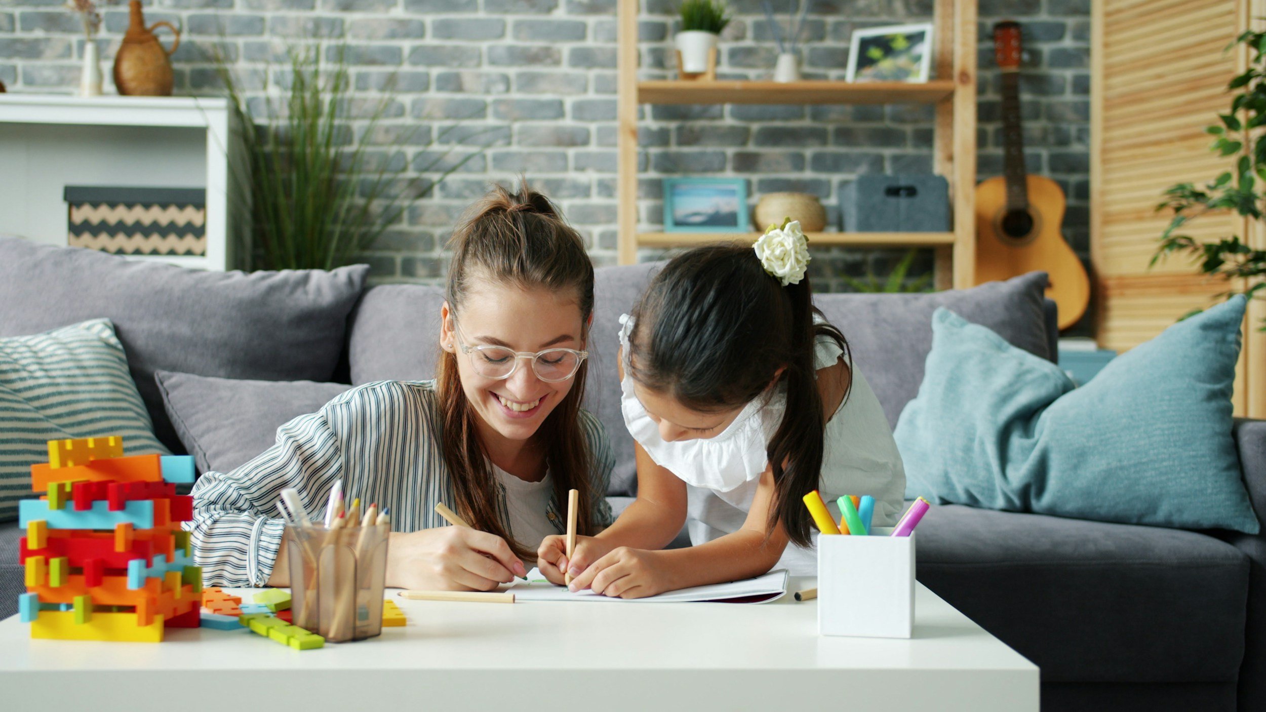 A mom and daughter are writing on a piece of paper.
