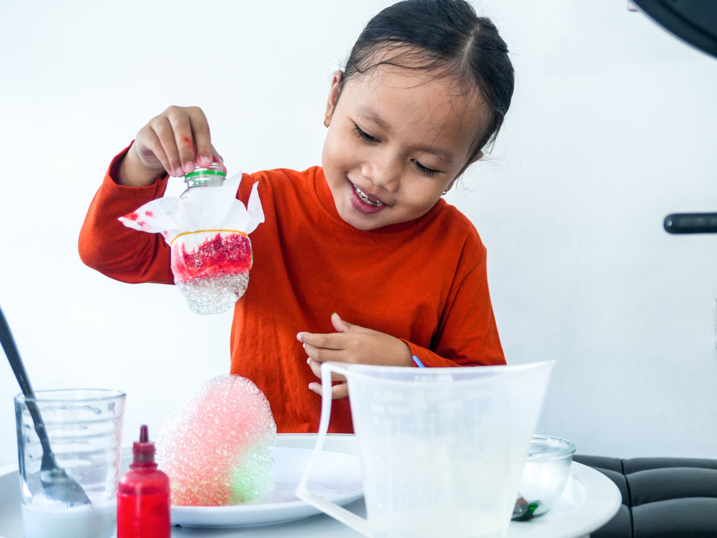 A little girl is using household tools to do a science experiment.