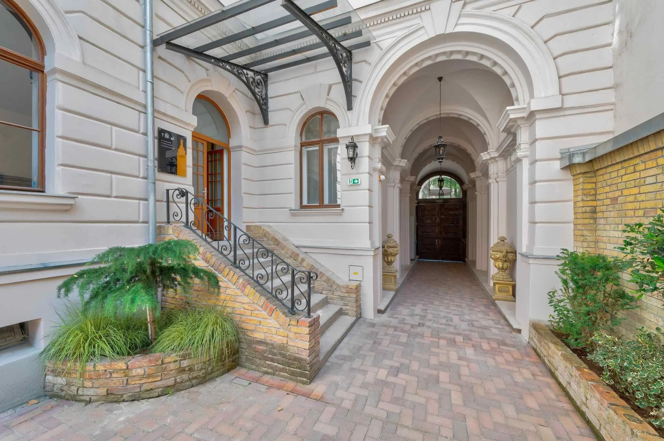 Entrance of a building with arched hallways, brick and stone architecture, and decorative lighting fixtures.